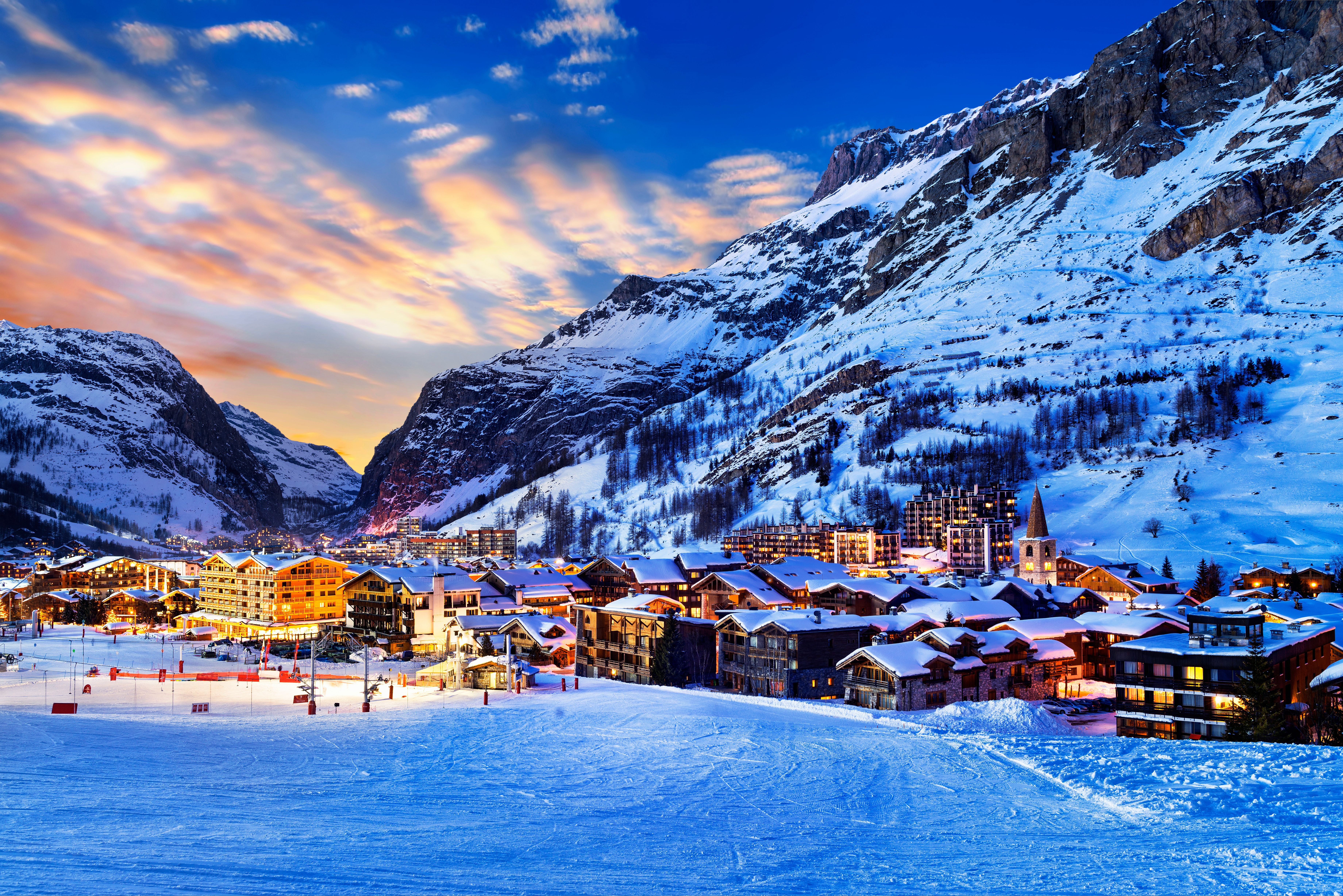 Winterlicher Blick auf Val d'Isère bei Sonnenuntergang, umgeben von verschneiten Alpenbergen.