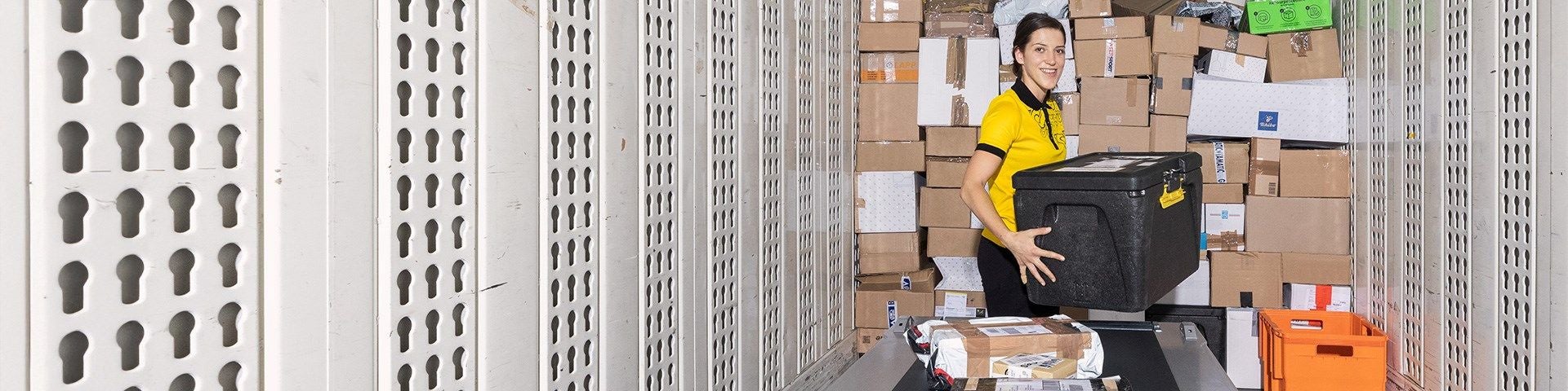 Eine Mitarbeiterin sortiert Pakete in einem Lagerraum der Post.