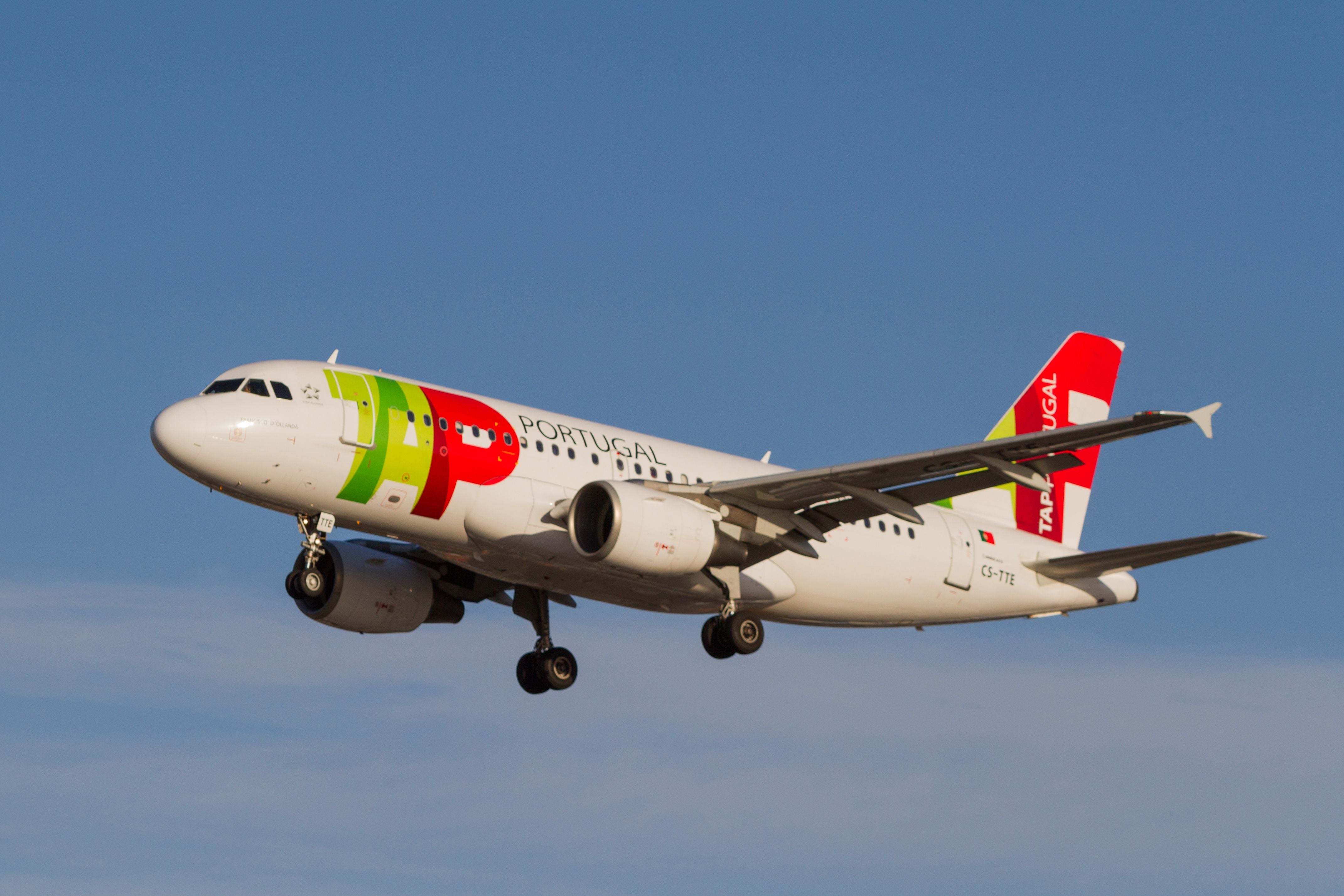 Ein Flugzeug der TAP Portugal im Landeanflug am Flughafen Oporto vor blauem Himmel.