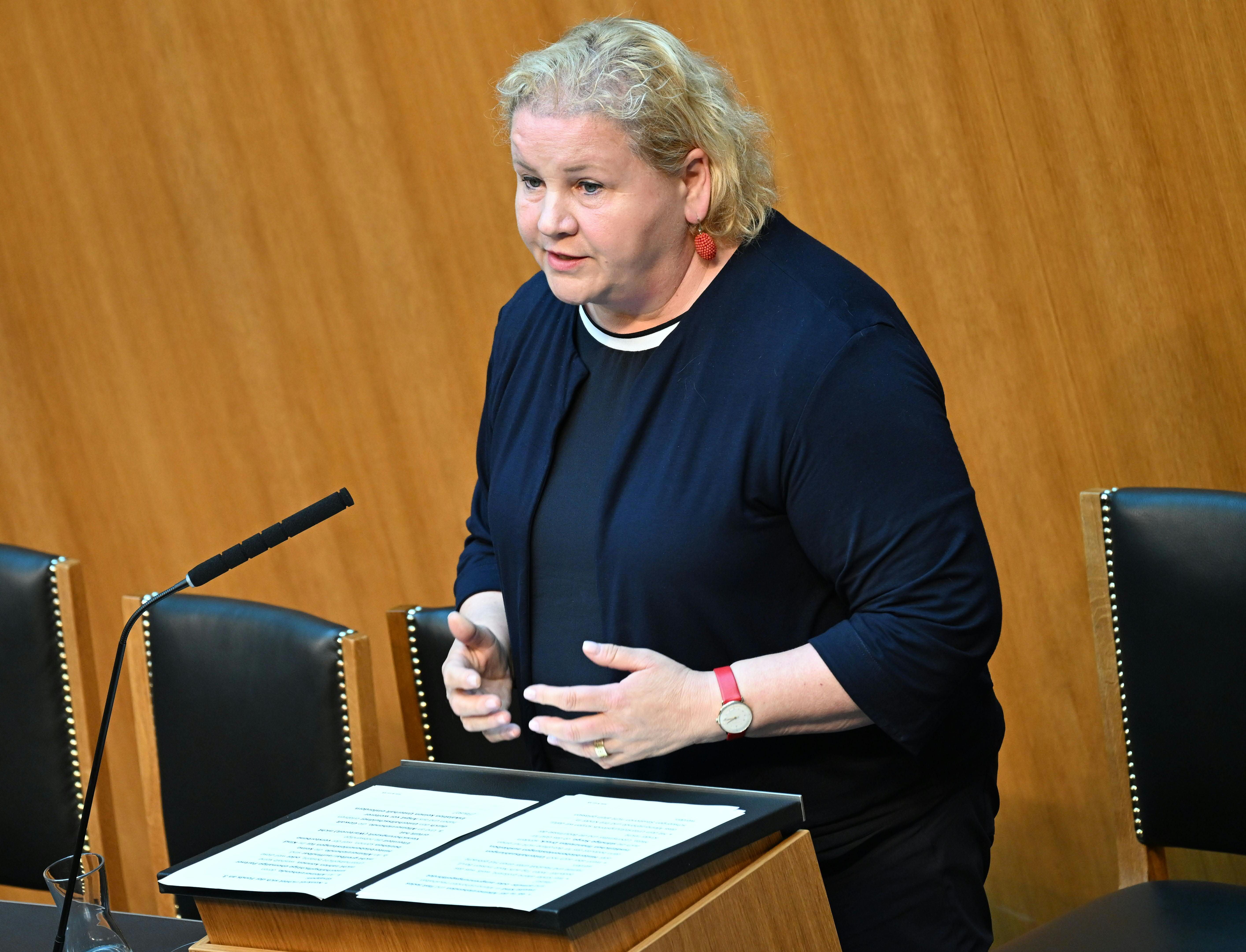 Eine Frau spricht im Parlament an einem Rednerpult, vor ihr liegen Manuskriptseiten.