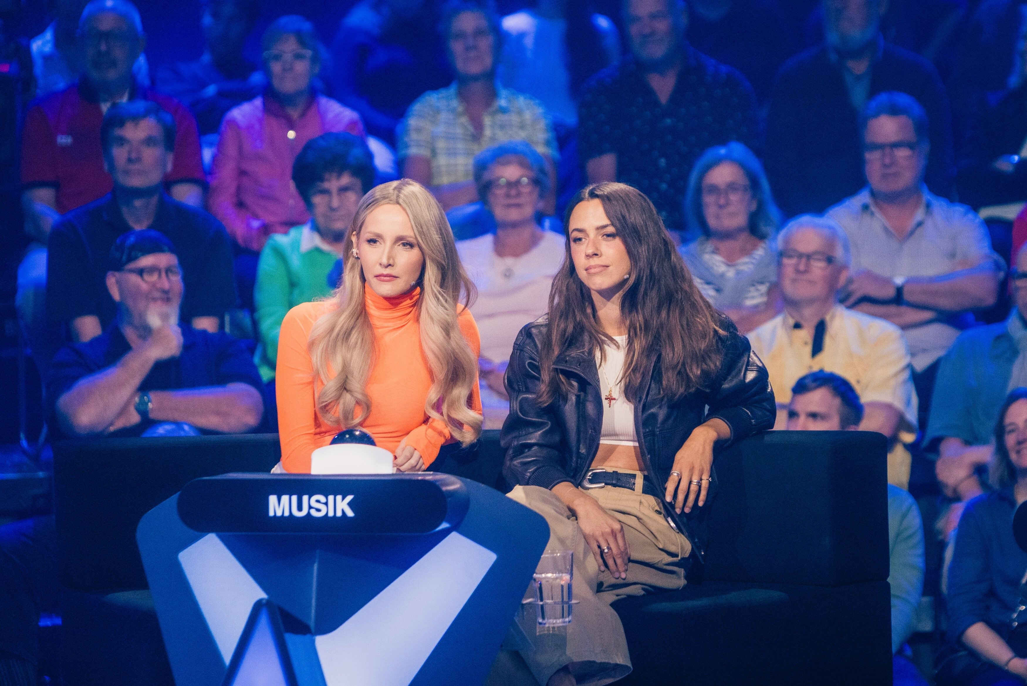 Zwei Frauen sitzen als Musik-Expertinnen in einer Quizshow vor Publikum im Studio.