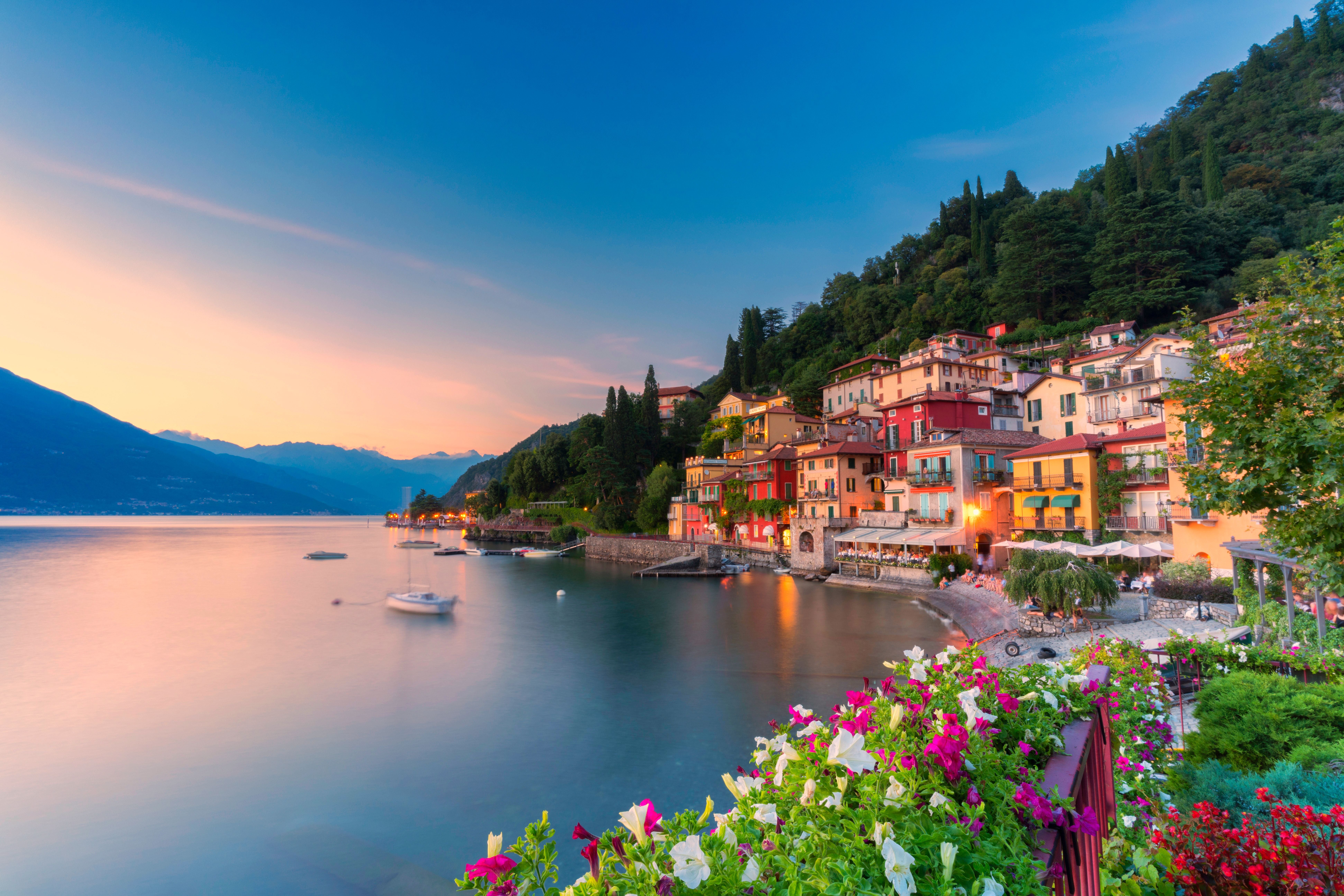 Bunte Häuser in Varenna am Comer See bei Sonnenuntergang, Blumen im Vordergrund.