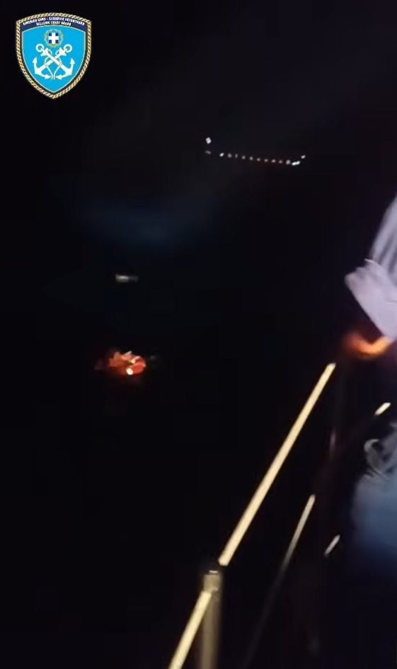 Nachtaufnahme einer Rettungsaktion auf See mit leuchtender Rettungsinsel im Wasser.