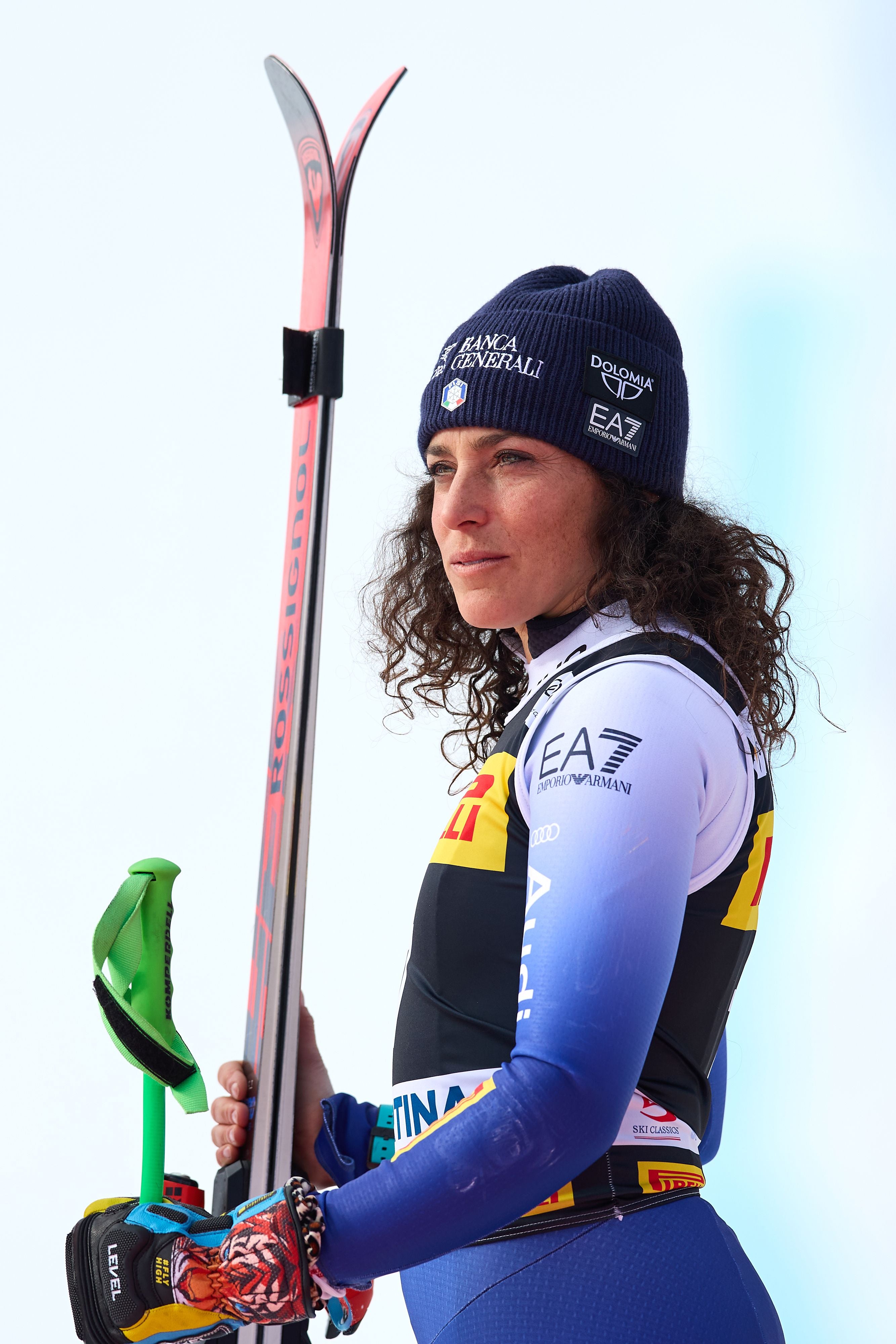 Eine Skifahrerin im Rennanzug hält Ski und blickt stolz zur Seite.