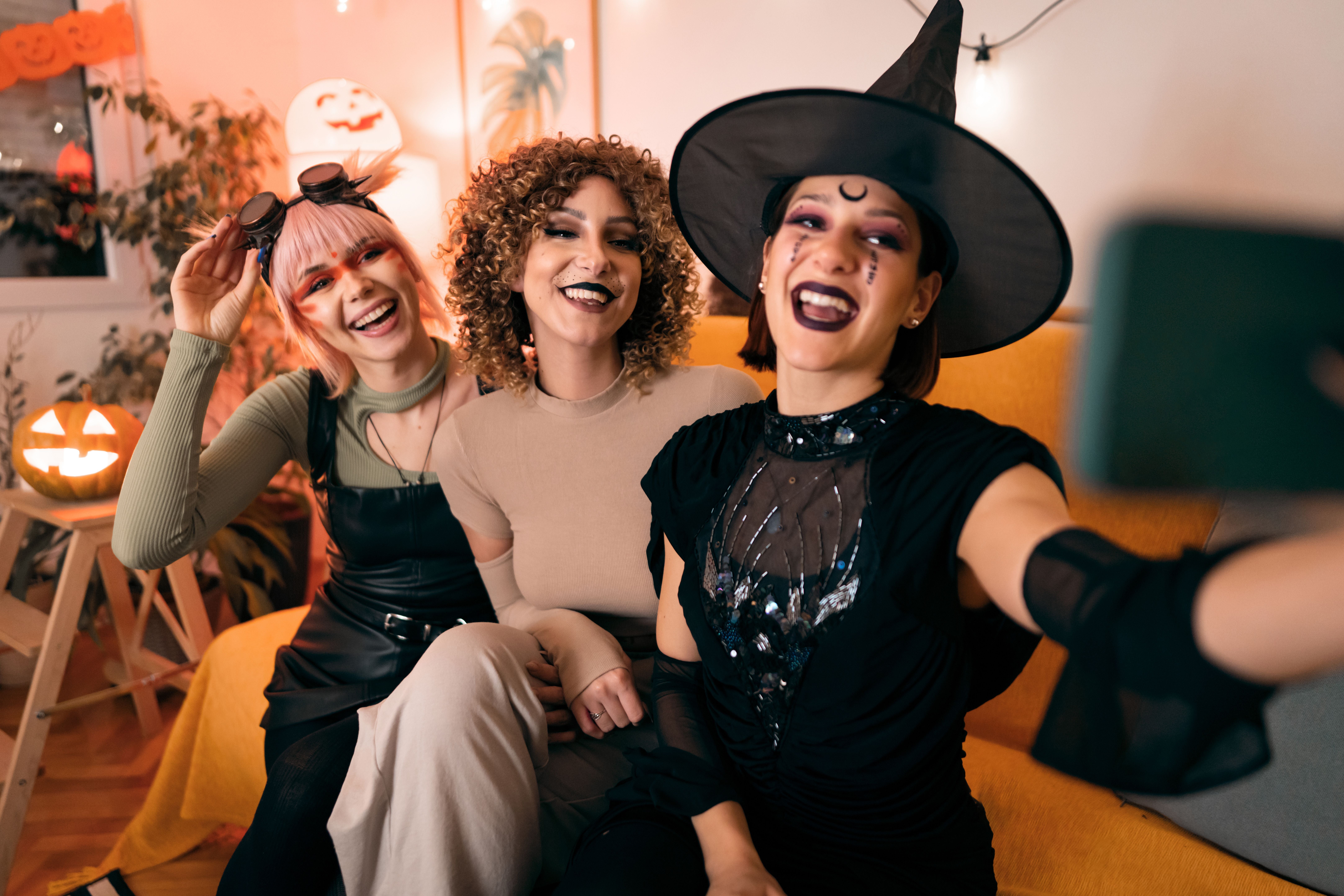 Drei junge Frauen machen in Halloweenkostümen ein Selfie auf einer Party.