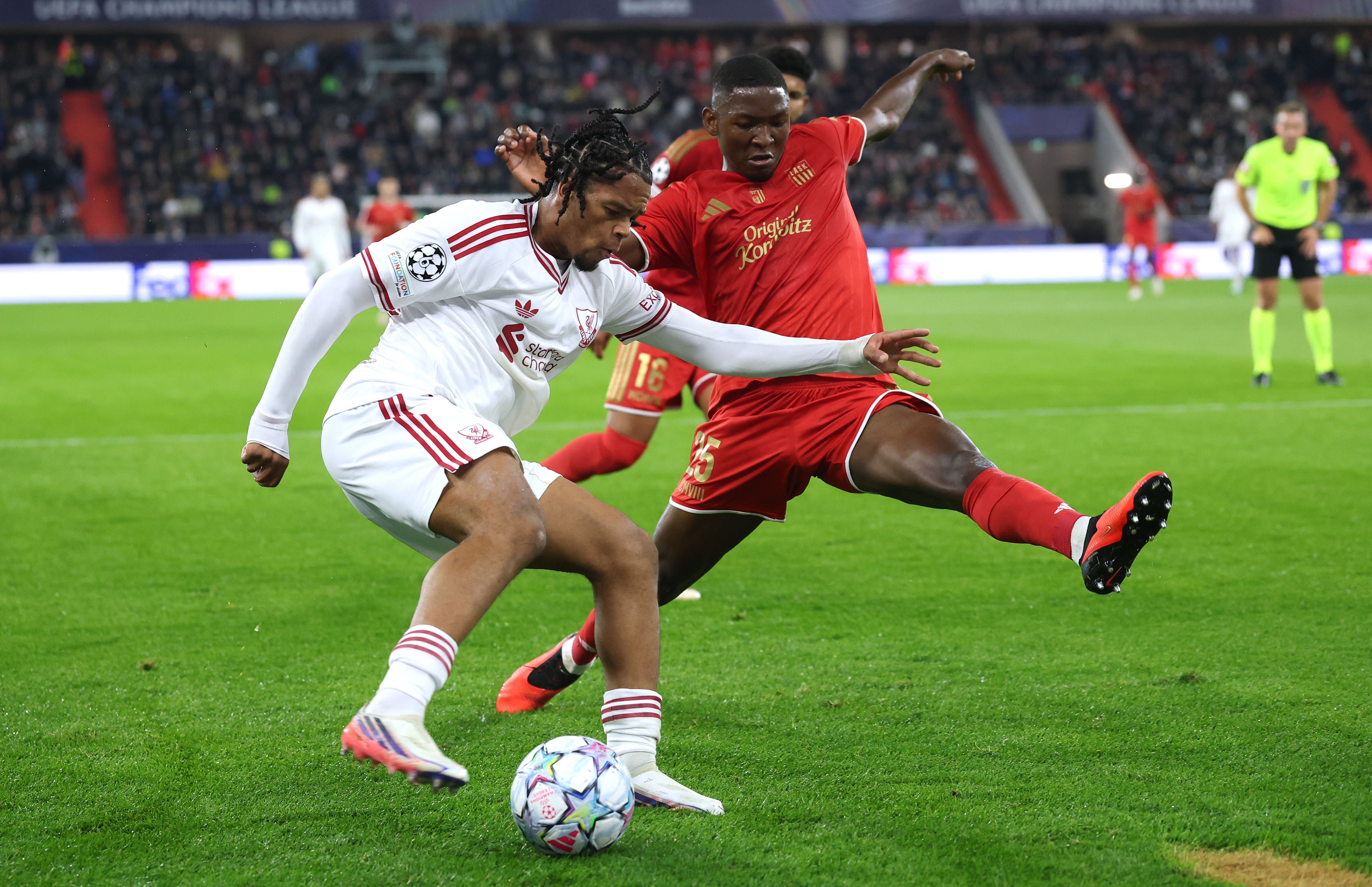 Zwei Fußballspieler kämpfen während eines Spiels um den Ball, einer in Weiß, einer in Rot.