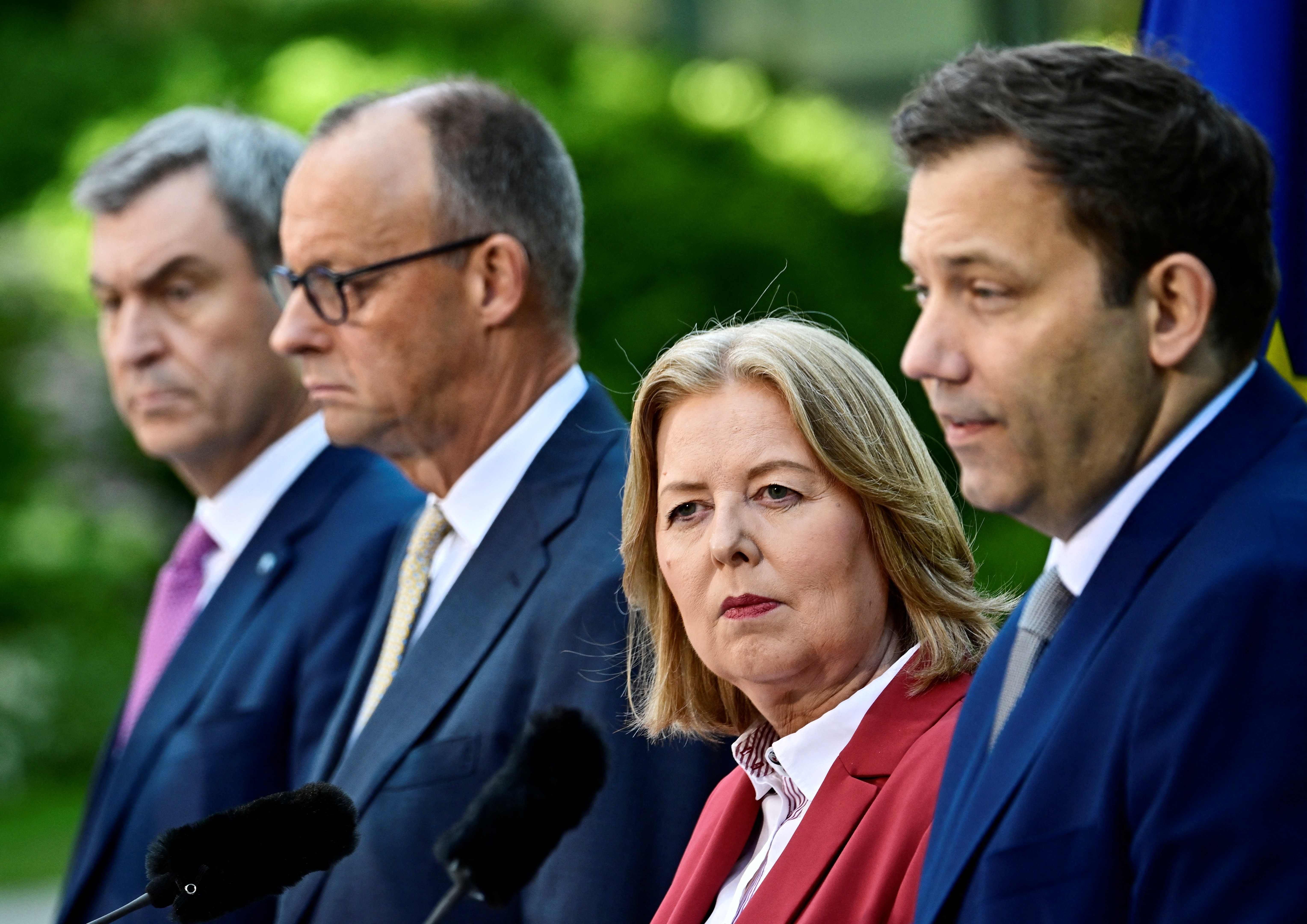 Vier Politiker stehen nebeneinander bei einer Pressekonferenz im Freien, Mikrofone sind sichtbar.