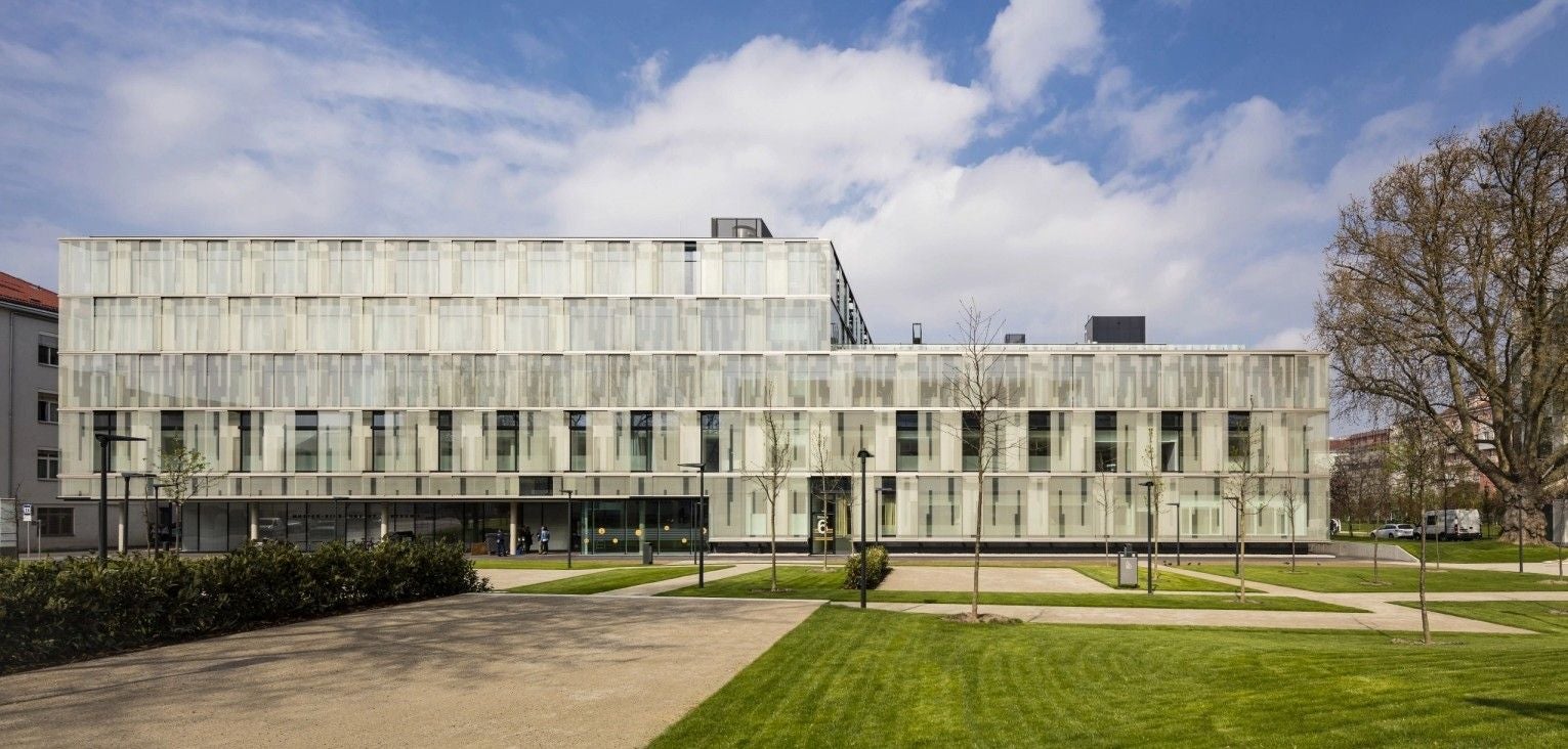 Moderne Glasfassade der Klinik Favoriten mit gepflegtem Rasen und Gehweg im Vordergrund.