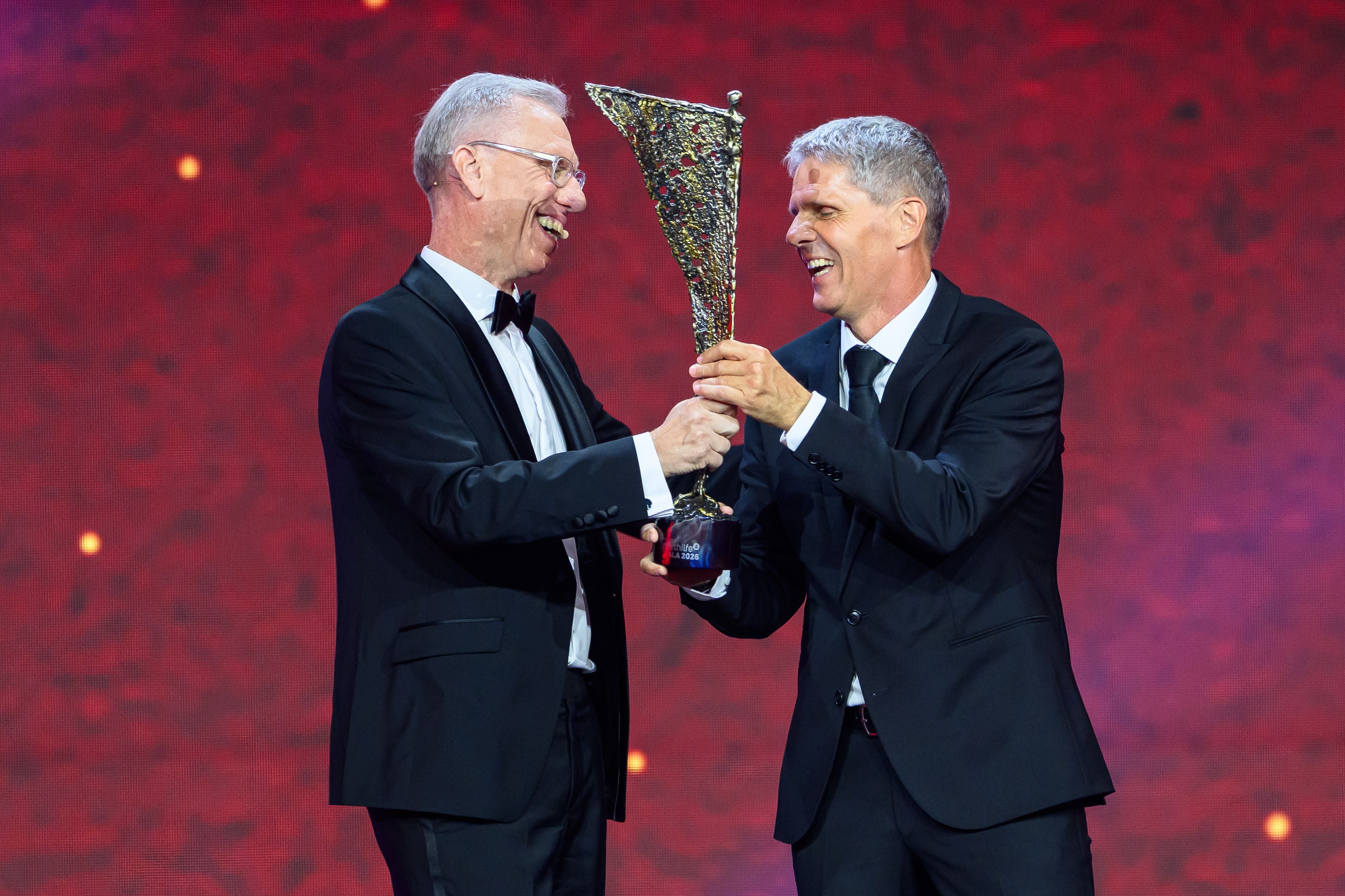 Didi Kühbauer und Peter Stöger halten gemeinsam grinsend die goldene NIKI-Trophäe auf der Bühne der Sporthilfe-Gala in den Händen.