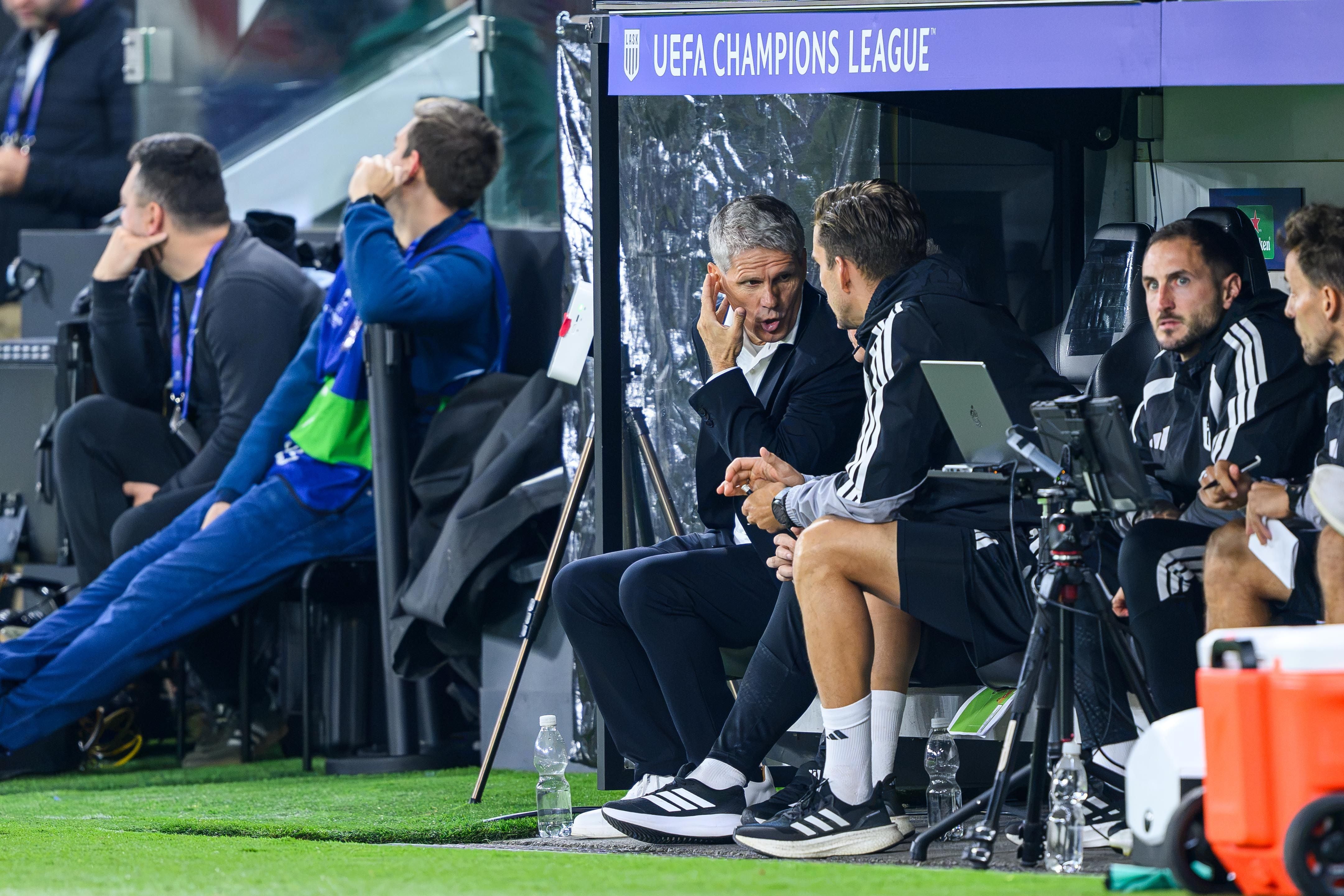 Trainer und Betreuer von LASK sitzen bei einem UEFA Champions League-Spiel auf der Bank.