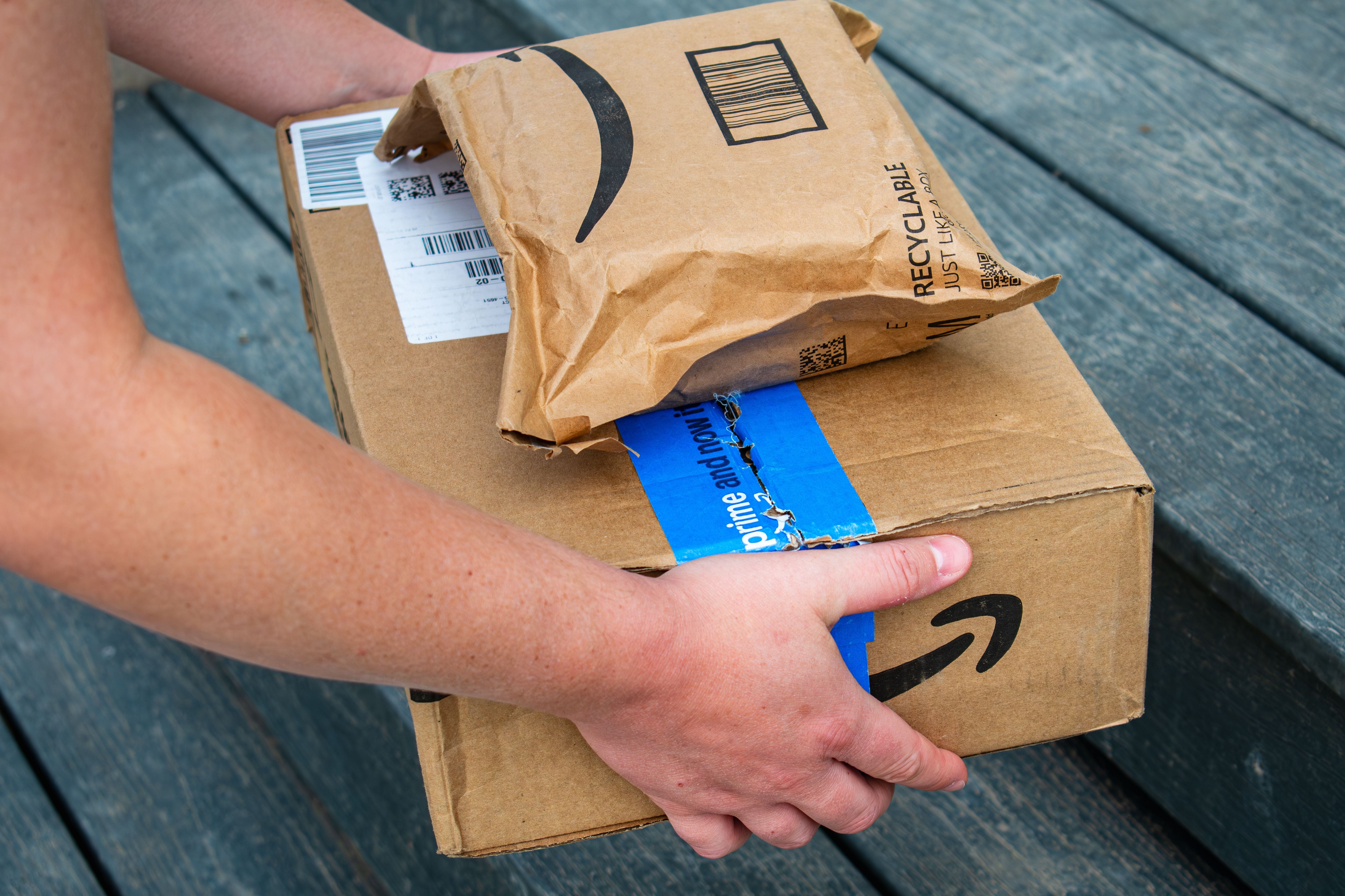 Ein Amazon-Bote stellt zwei Amazon Prime-Pakete auf eine Haustreppe.