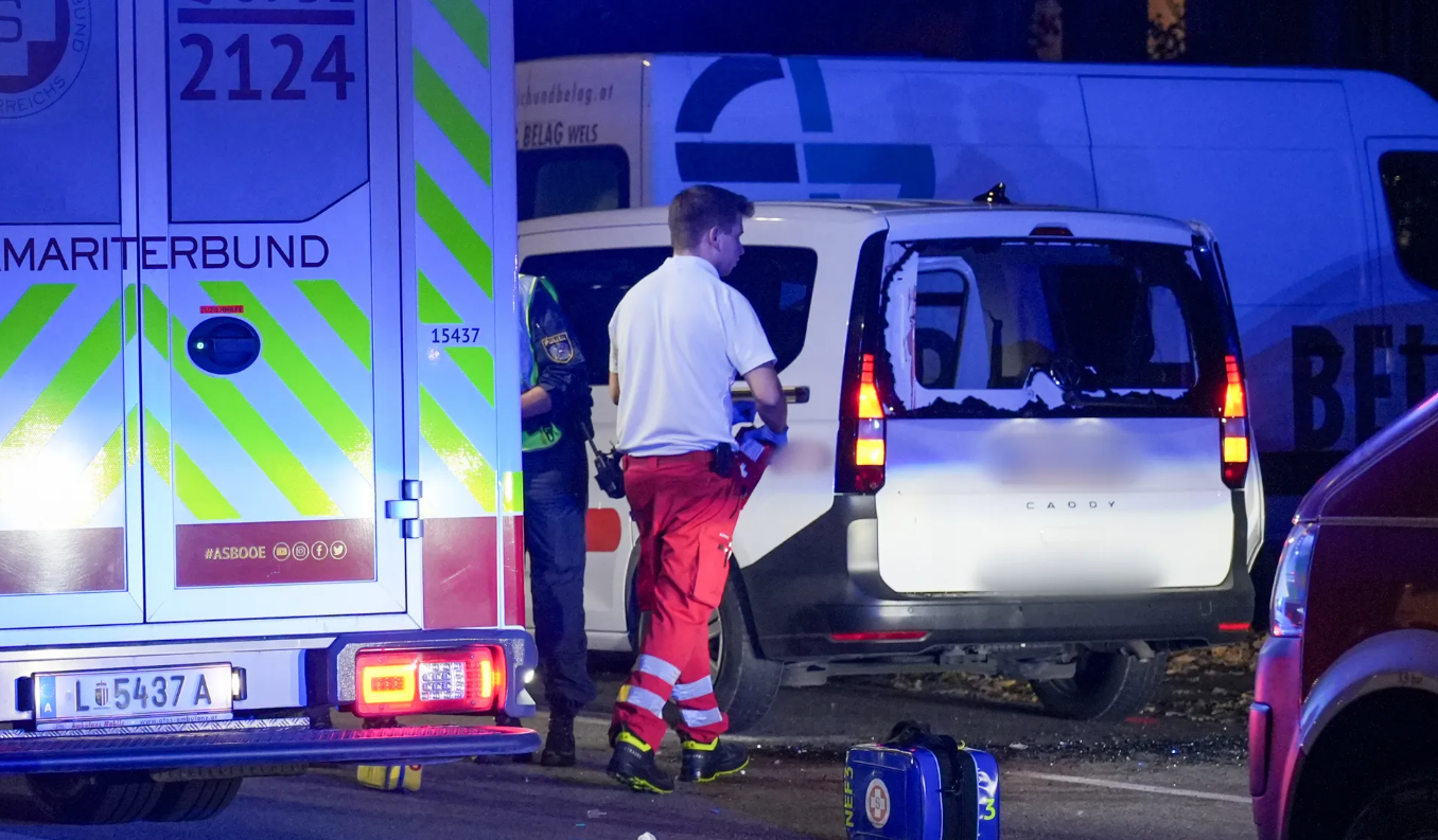 Rettungskräfte und Polizei arbeiten an einem Unfallort mit beschädigtem Auto in Linz bei Nacht.