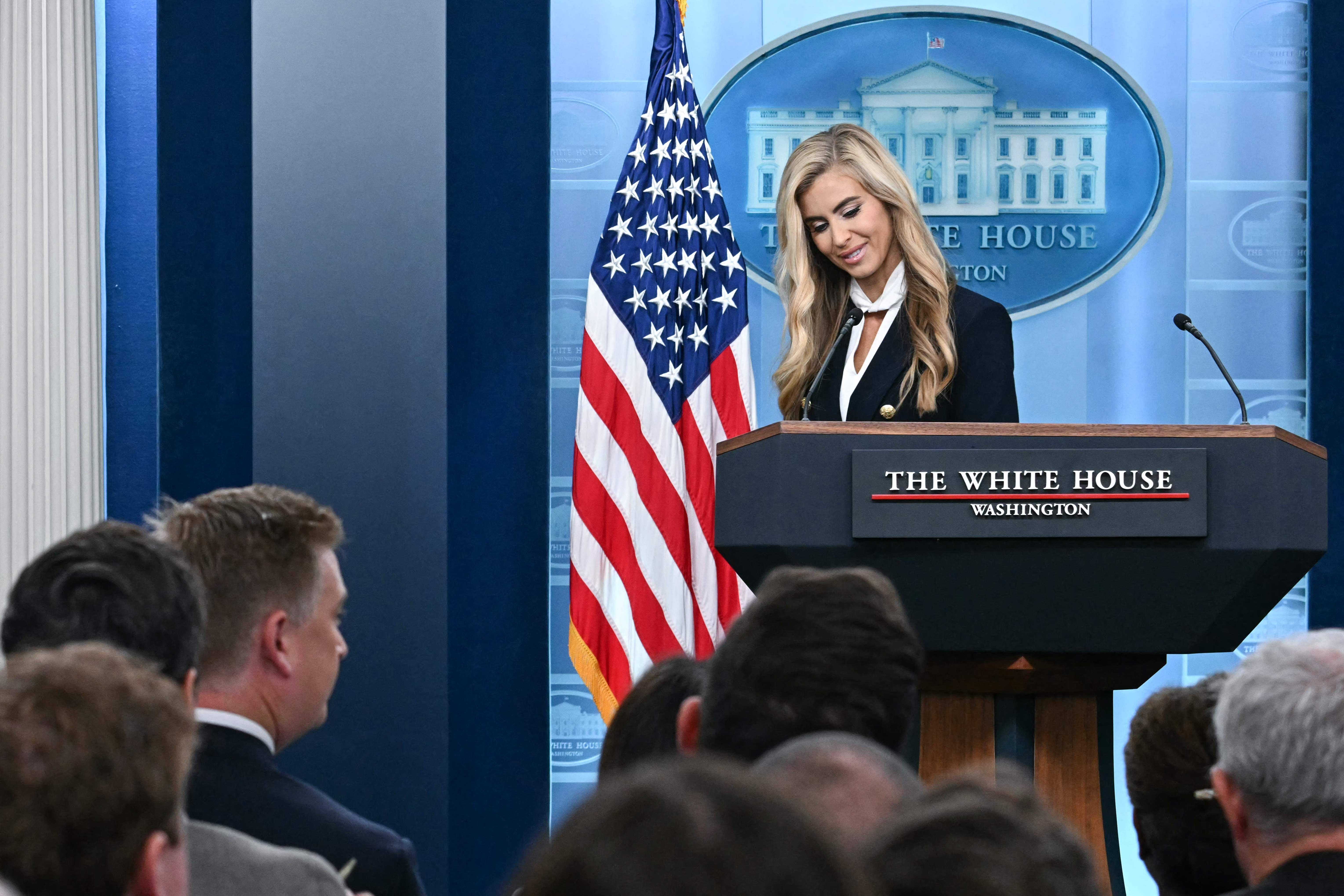 Eine Frau steht am Rednerpult im Briefing Room des Weißen Hauses vor Publikum und US-Flagge.