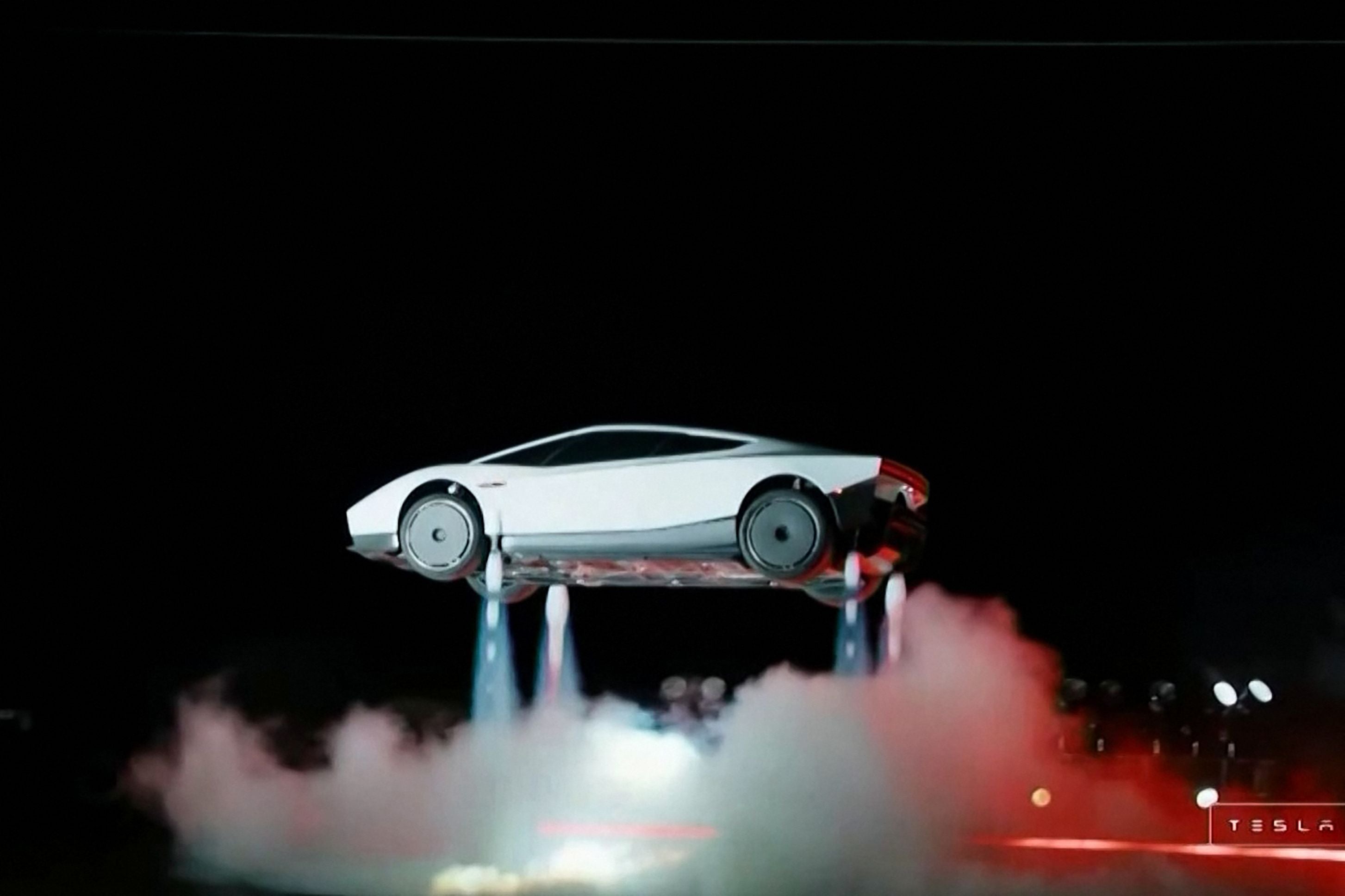 Ein weißer Tesla Roadster schwebt mit Raketenantrieb über dem Boden, Rauch steigt auf.