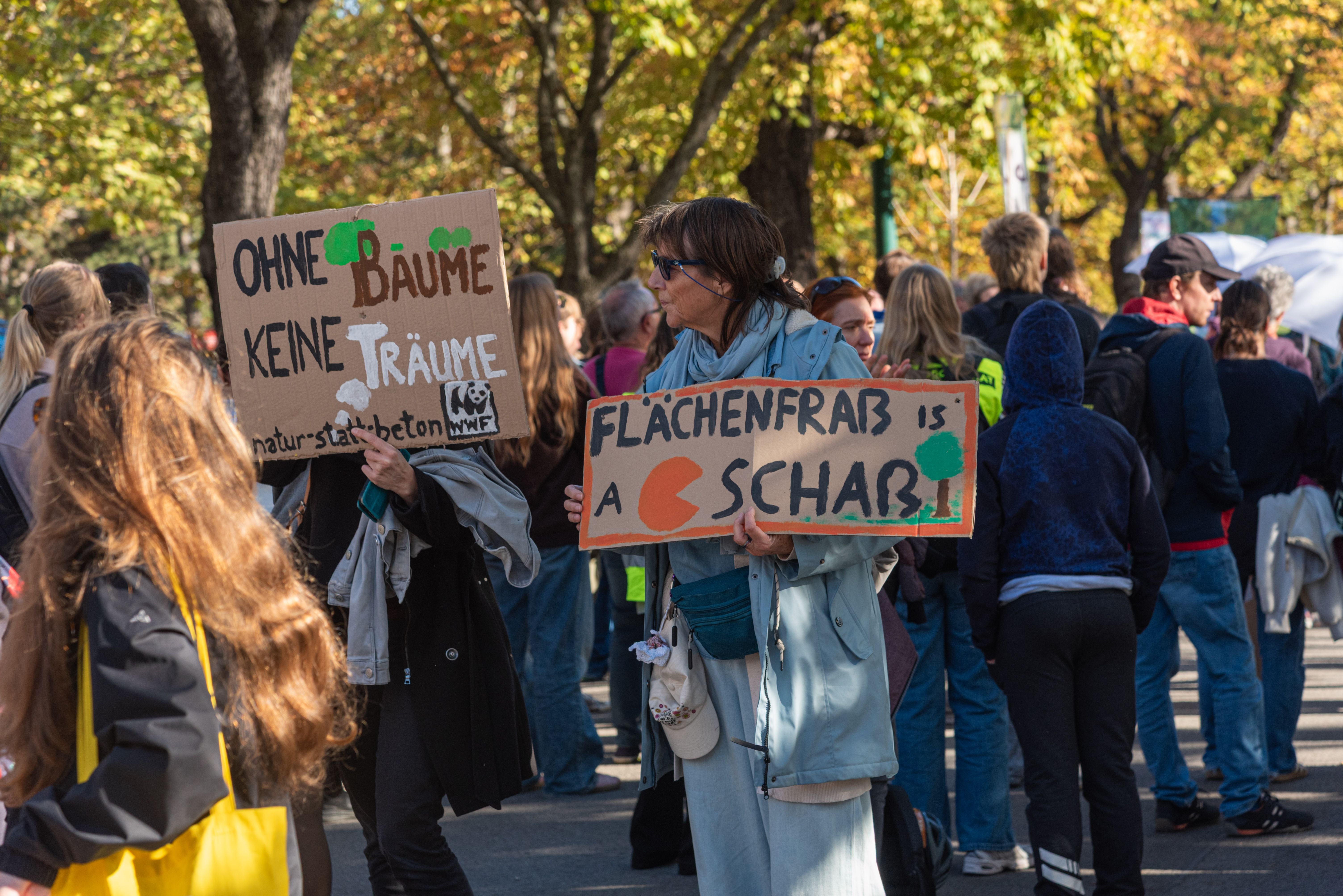 Menschen beim Klimastreik halten Schilder mit Sprüchen zum Schutz von Bäumen und gegen Flächenfraß.