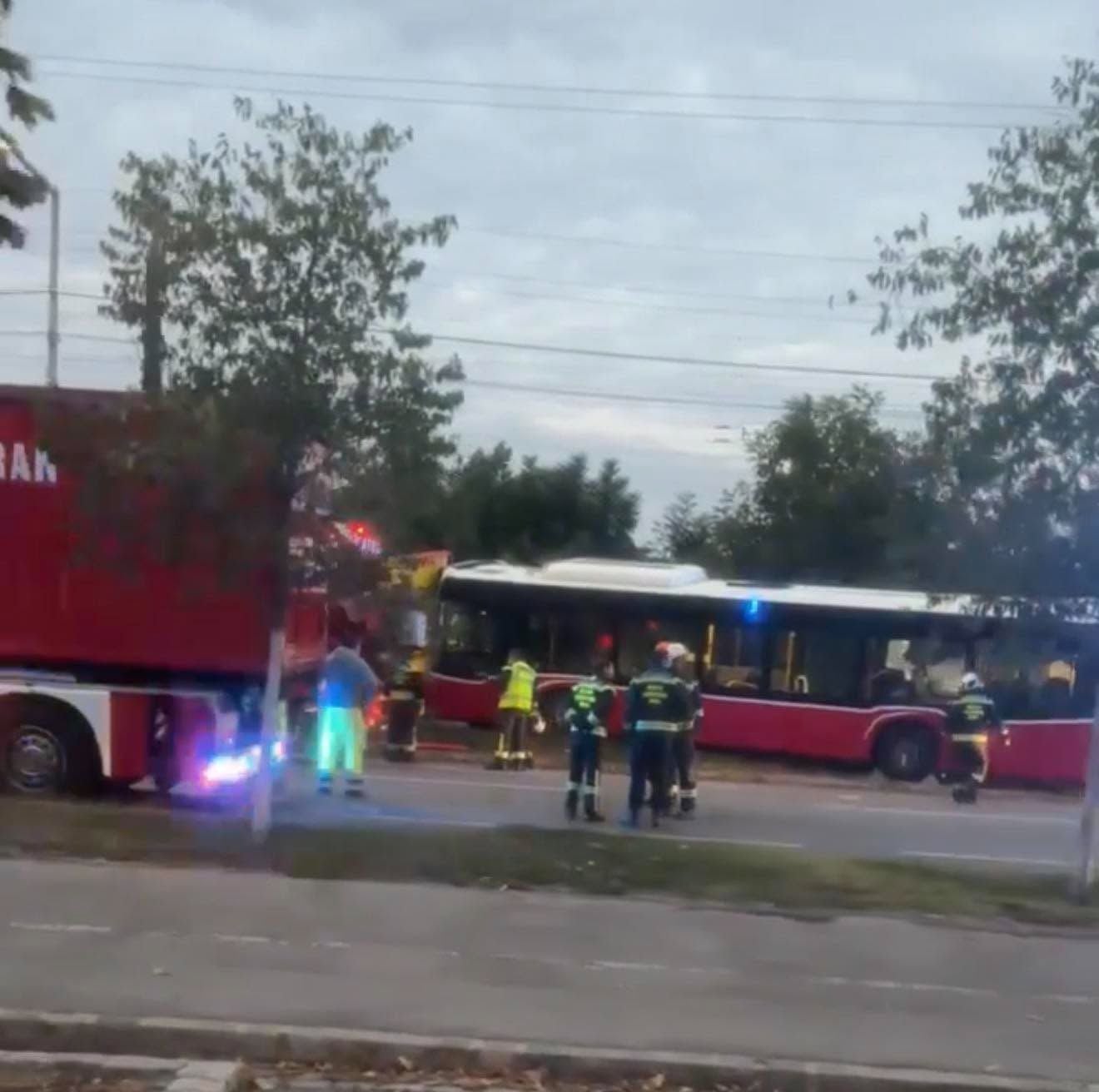 Feuerwehrleute und Rettungskräfte stehen neben einem roten Bus nach einem Unfall.