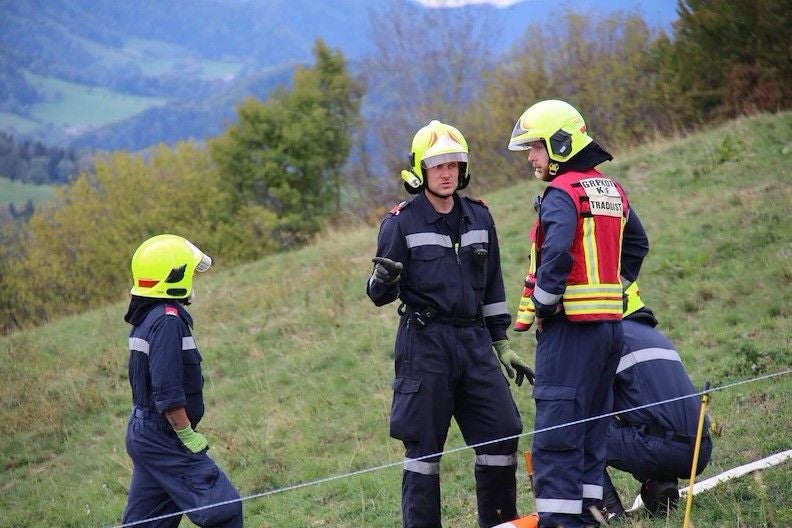 Vier Feuerwehrleute mit Schutzhelmen besprechen sich auf einer Wiese während einer Übung.