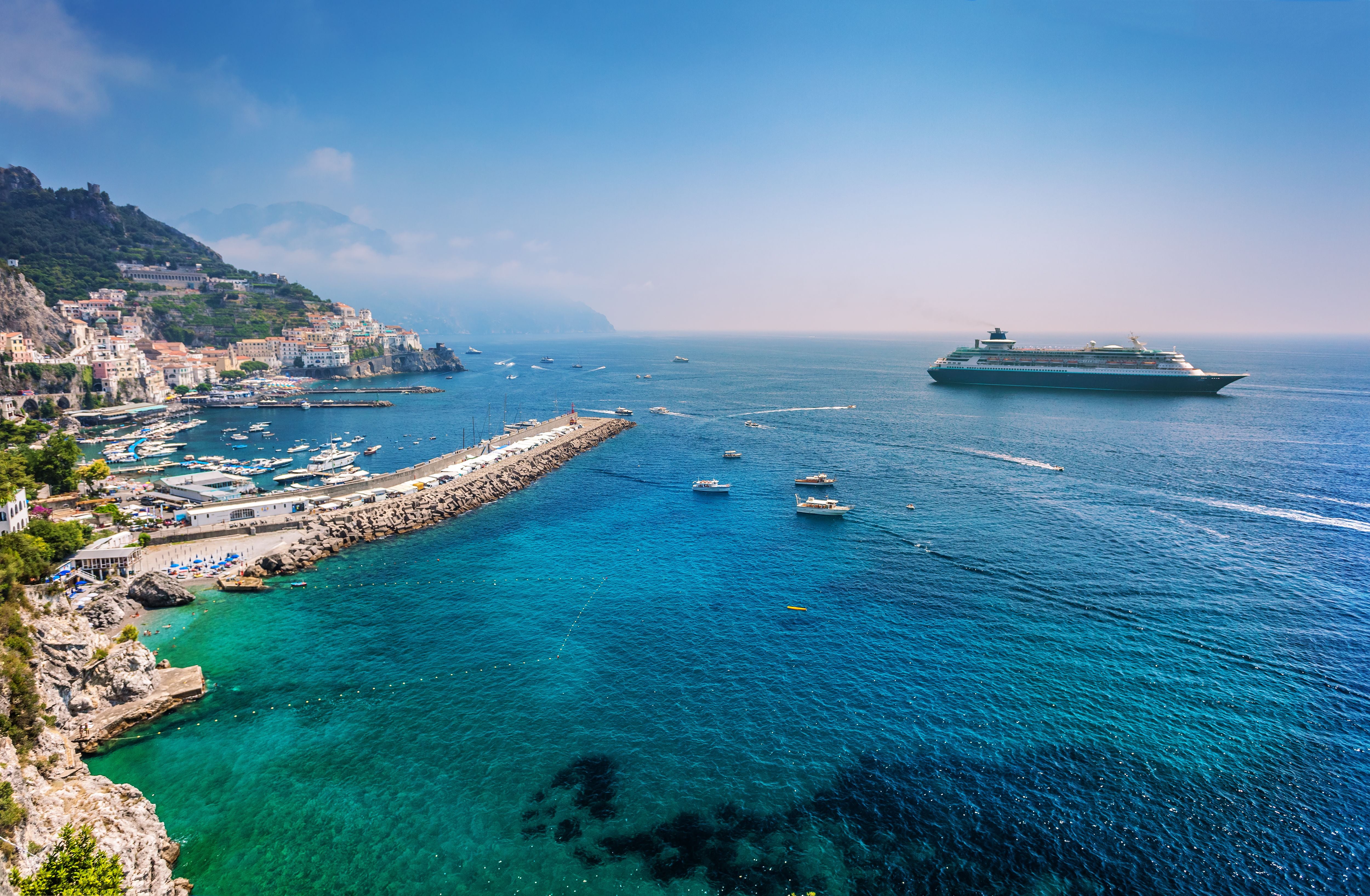 Kreuzfahrtschiff vor der Amalfi-Küste bei Salerno, Italien, mit klarem blauem Meer und Hafen.
