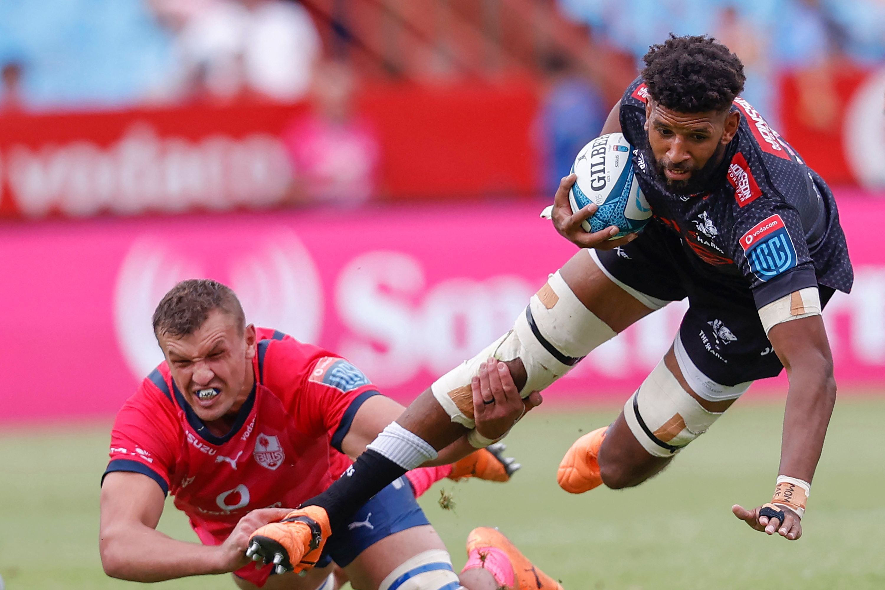 Ein Rugbyspieler der Sharks wird während eines Spiels von einem Bulls-Spieler zu Boden gezogen.