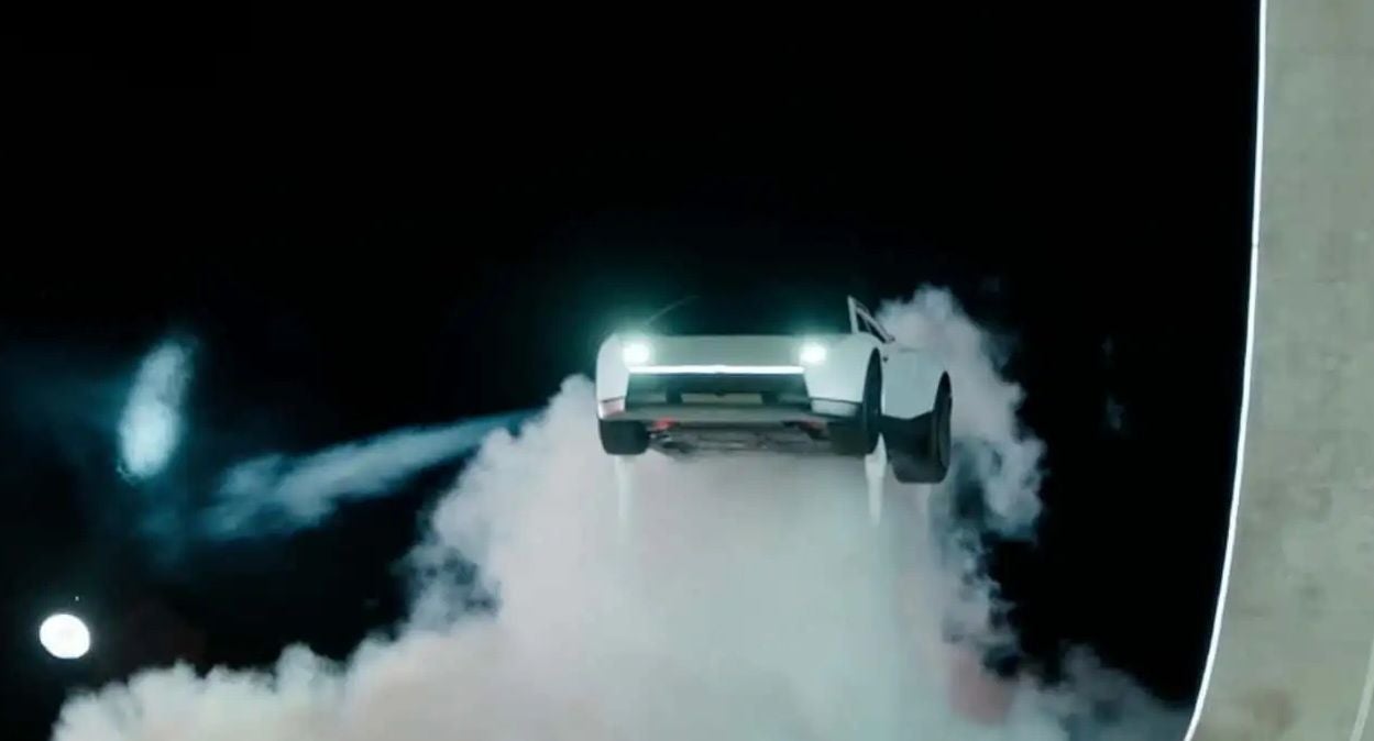 Ein Tesla Roadster schwebt mit Scheinwerfern und Rauch im Dunkeln in der Luft.