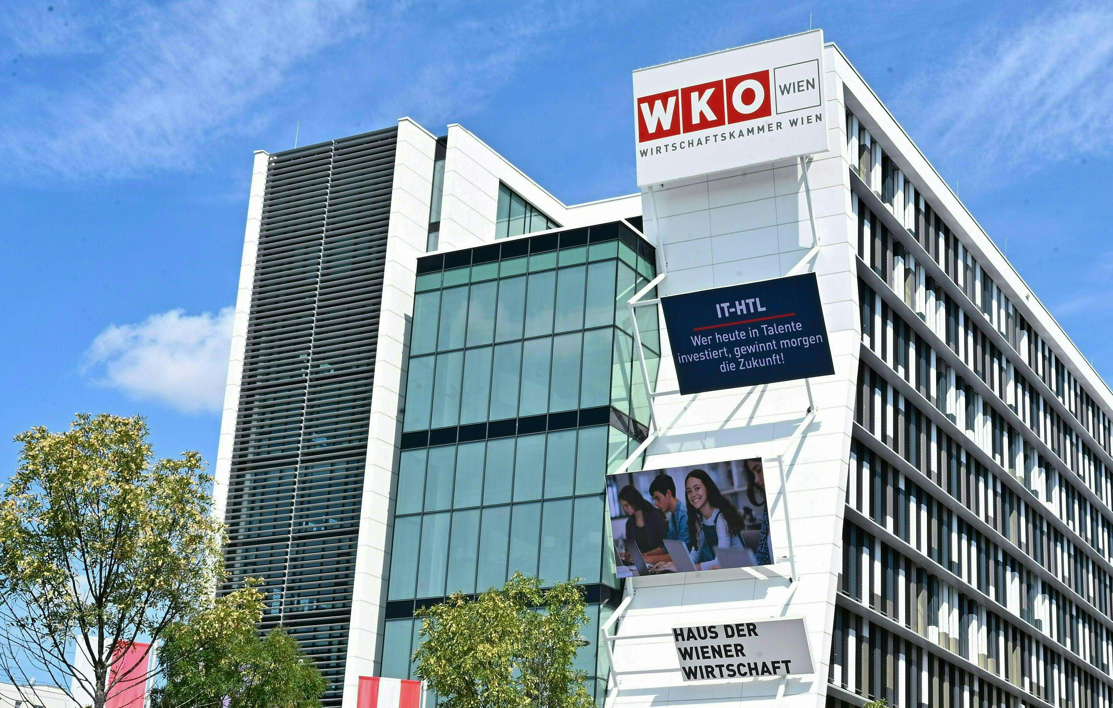 Außenansicht des Gebäudes der Wirtschaftskammer Wien mit Schildern und Glasfassade.