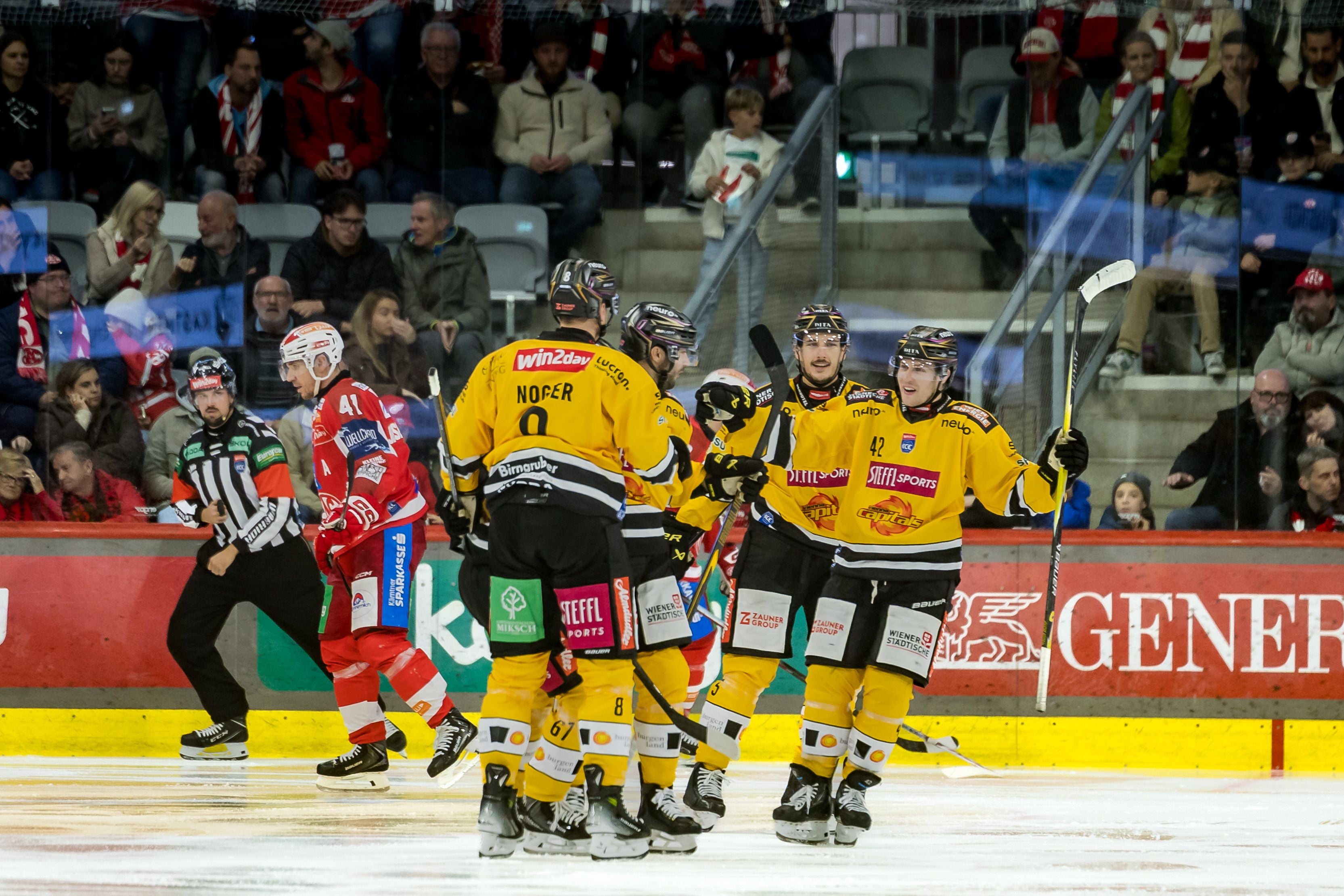 Die Spieler der Vienna Capitals jubeln in gelb-schwarzen Trikots auf dem Eis, während KAC-Akteure enttäuscht abdrehen.