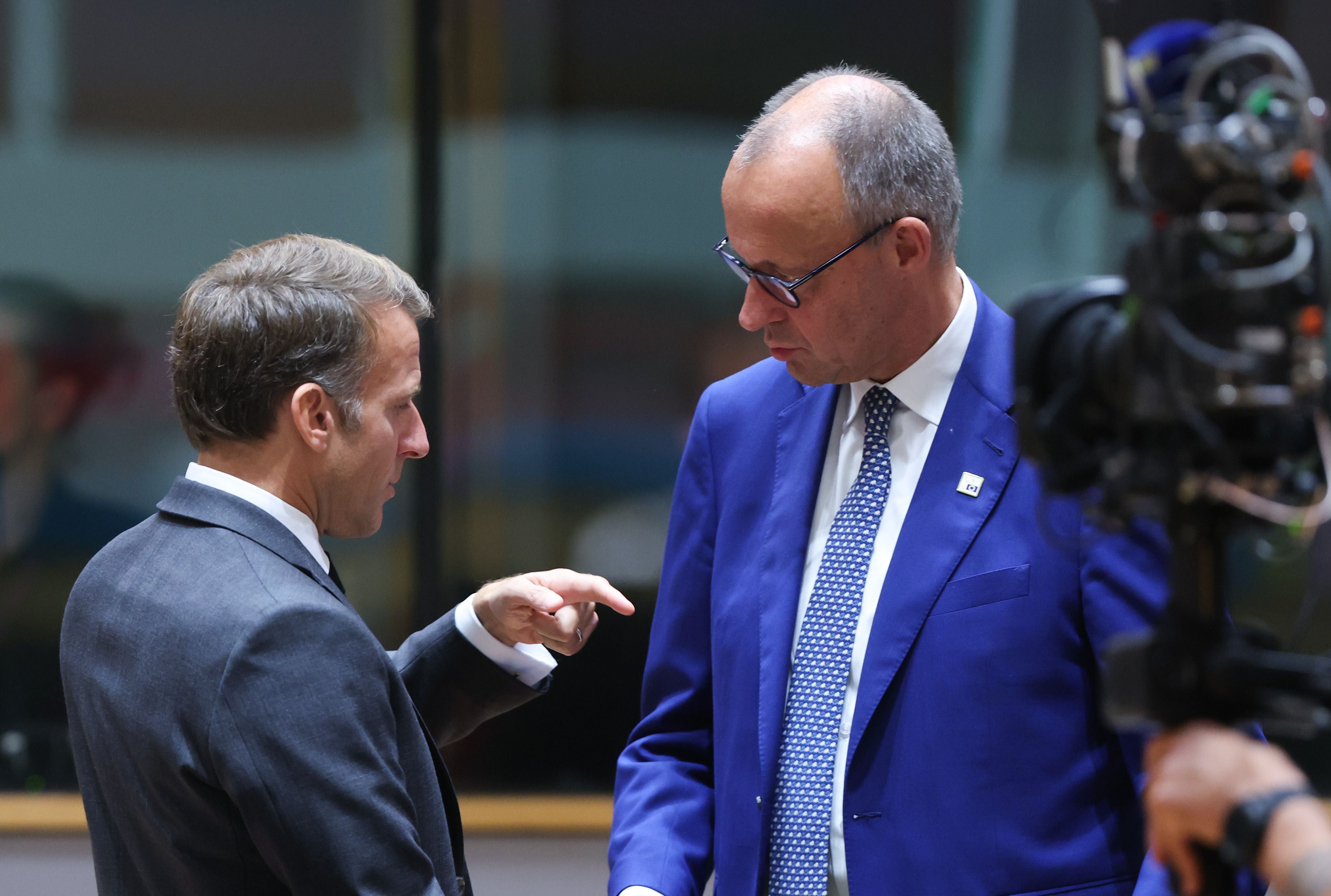 Zwei Männer im Anzug unterhalten sich ernsthaft bei einem Gipfeltreffen, ein Kameramann filmt sie.