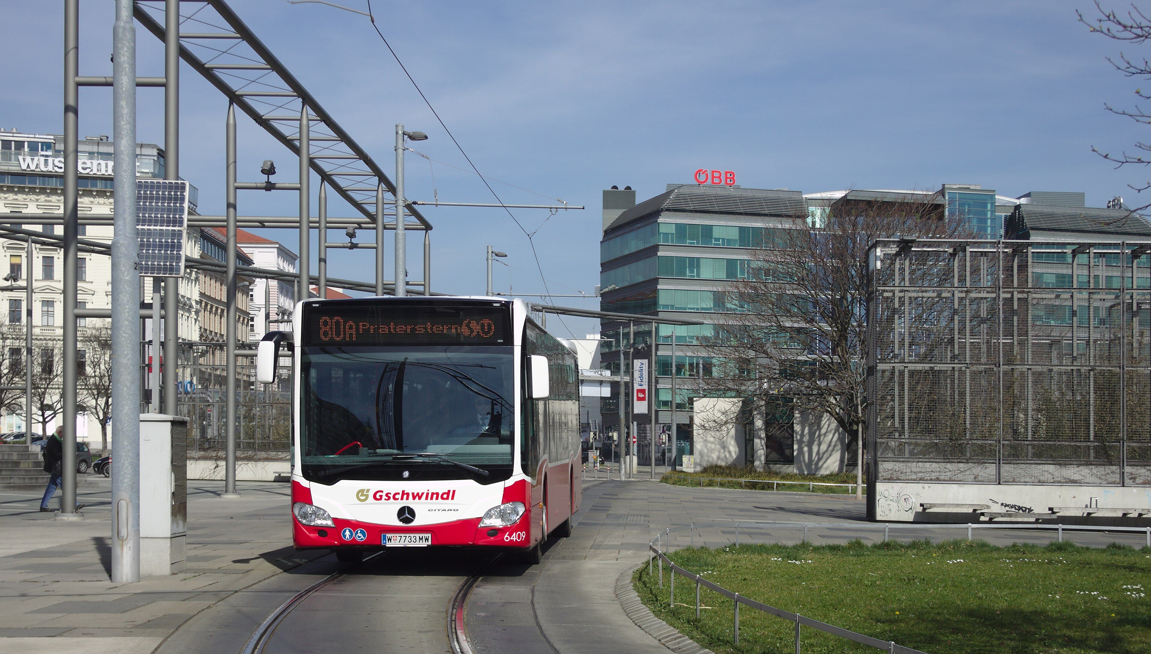 Ein Linienbus der Linie 80A fährt auf einer Stadtstraße in Wien bei sonnigem Wetter.