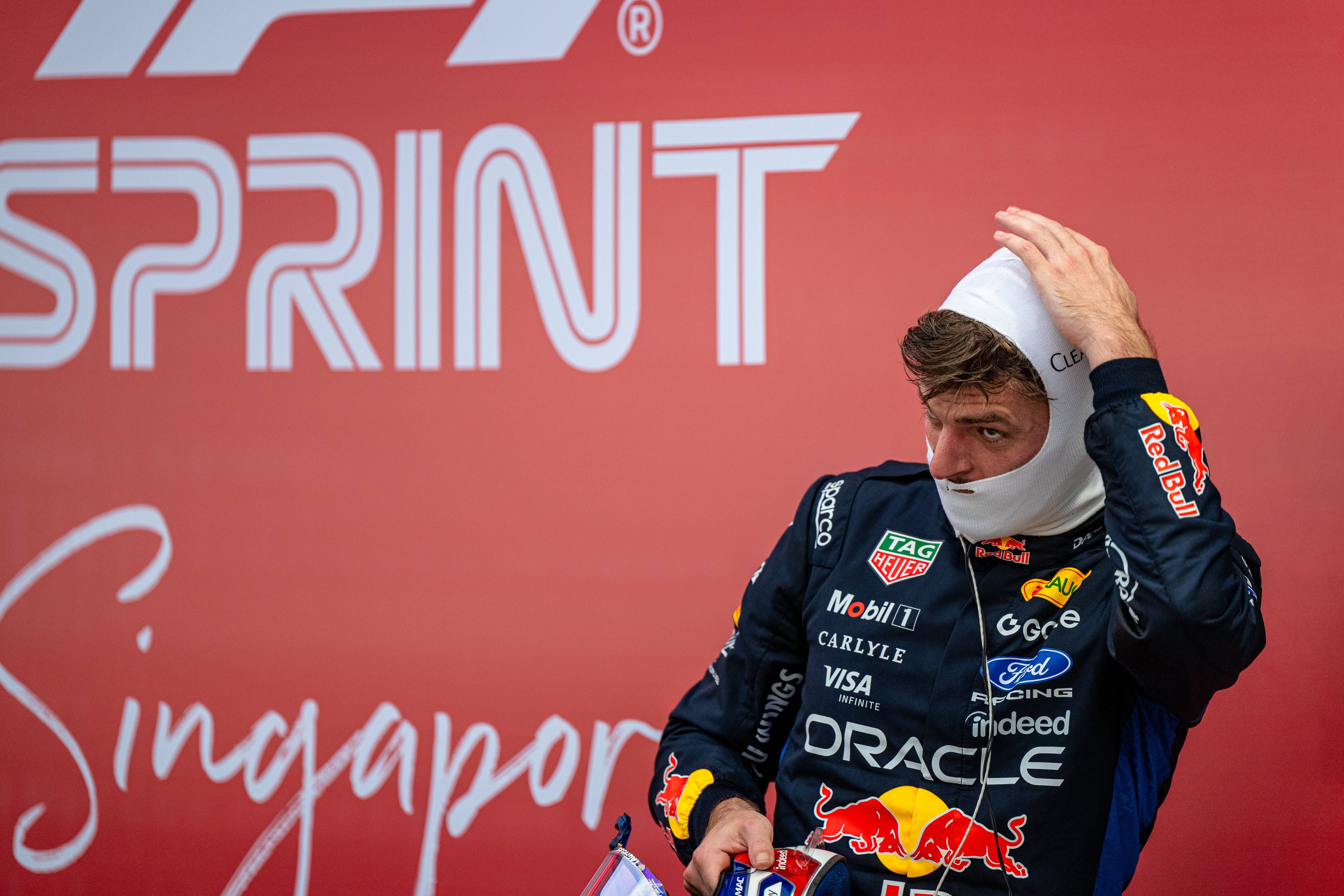 Formel-1-Fahrer im Red-Bull-Rennanzug setzt die Sturmhaube vor einem roten "Sprint"-Plakat auf.