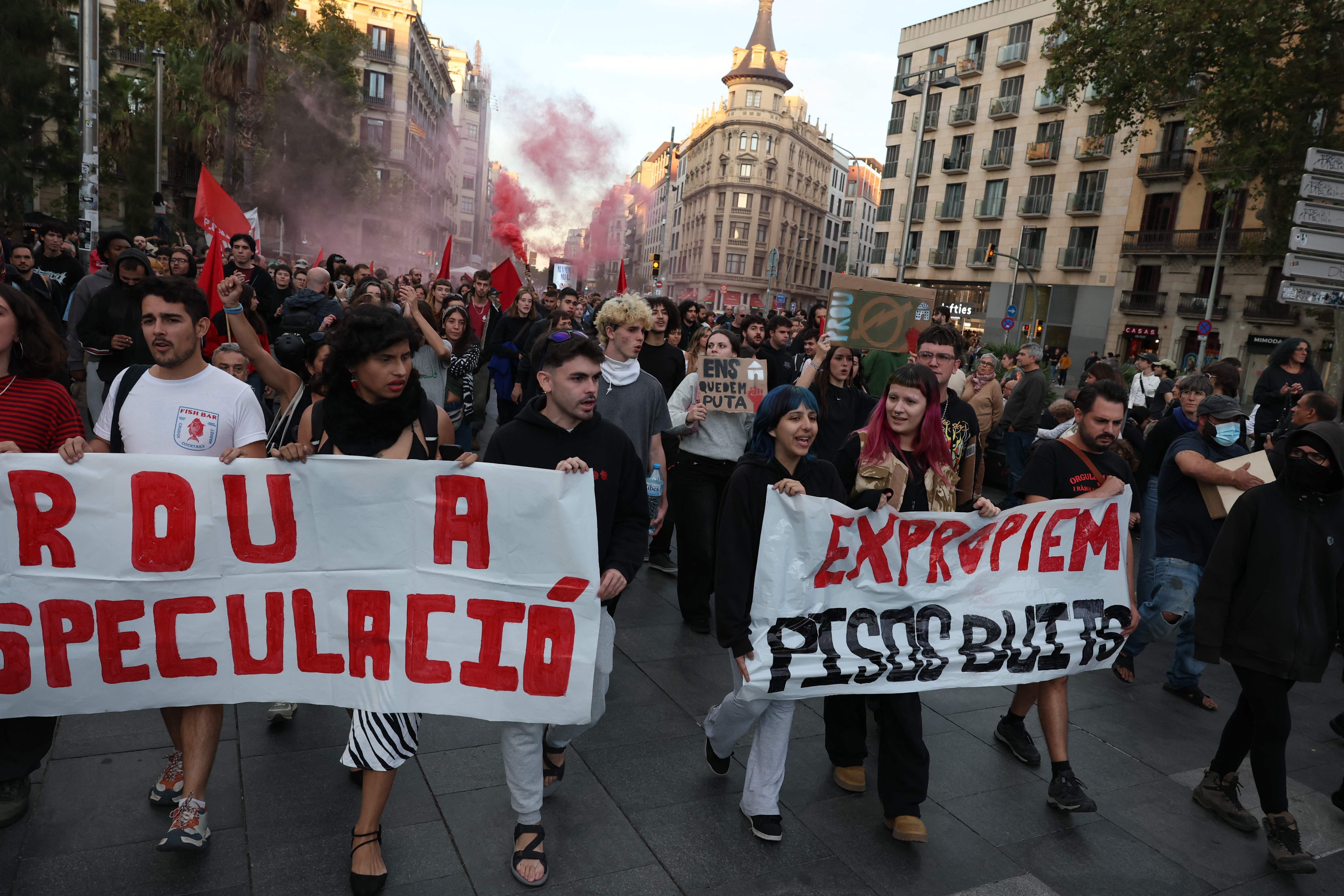 Menschen demonstrieren mit Transparenten gegen Wohnungsspekulation auf einer Straße in Barcelona.