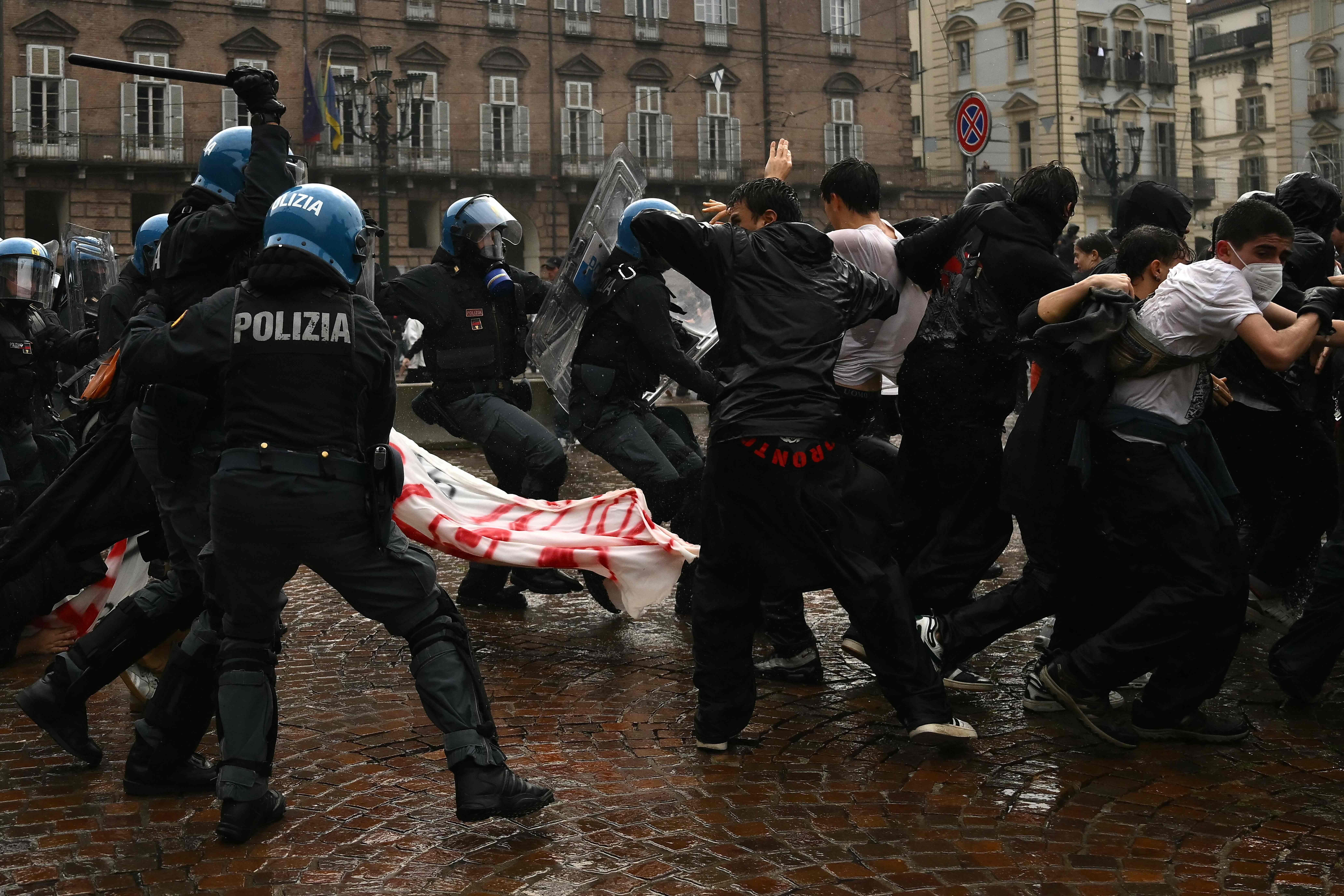 Polizisten in Schutzkleidung stoßen bei einer Demonstration auf dem Platz mit Protestierenden zusammen.