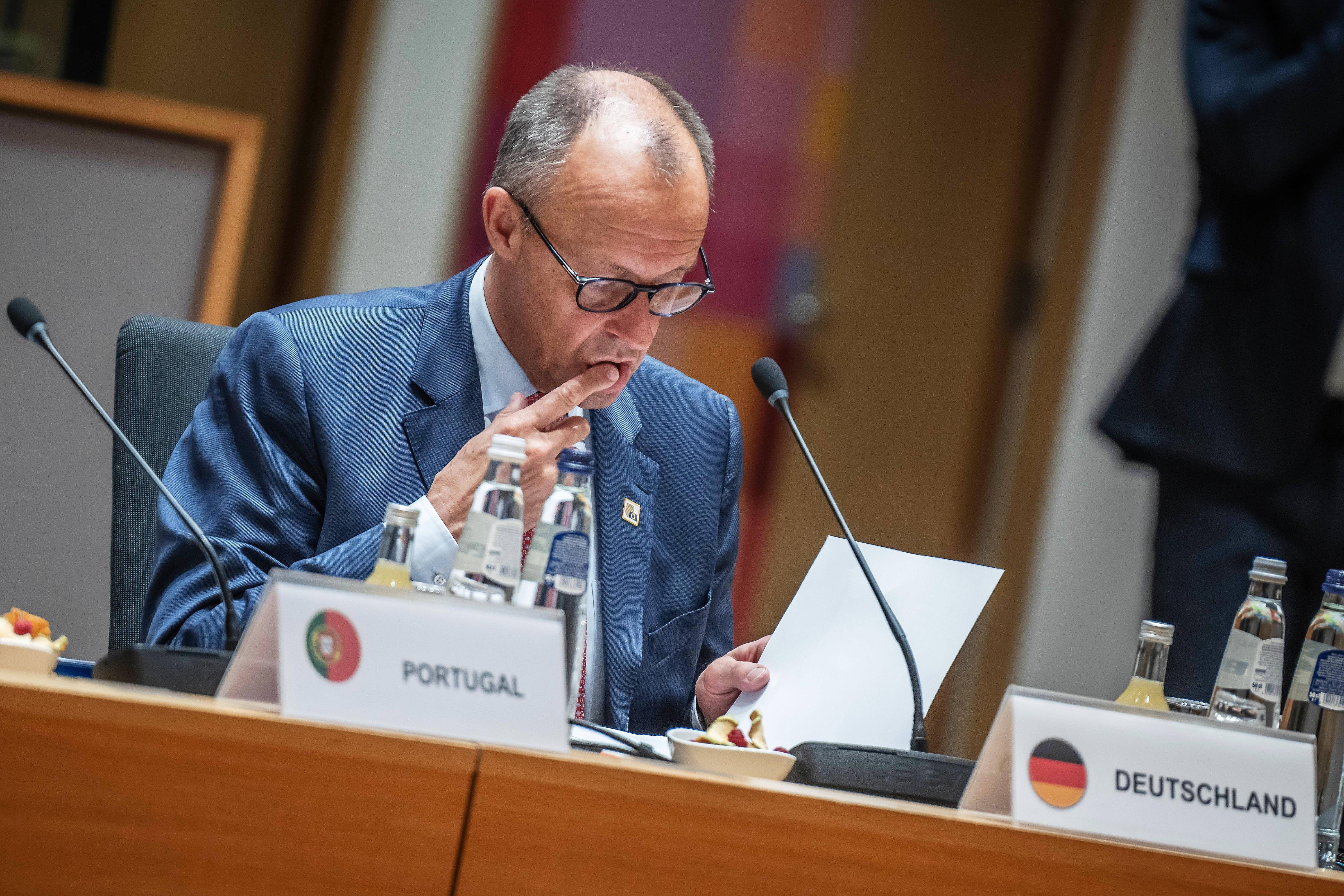 Ein Mann im Anzug liest konzentriert ein Dokument bei einem EU-Gipfeltreffen am Tisch.