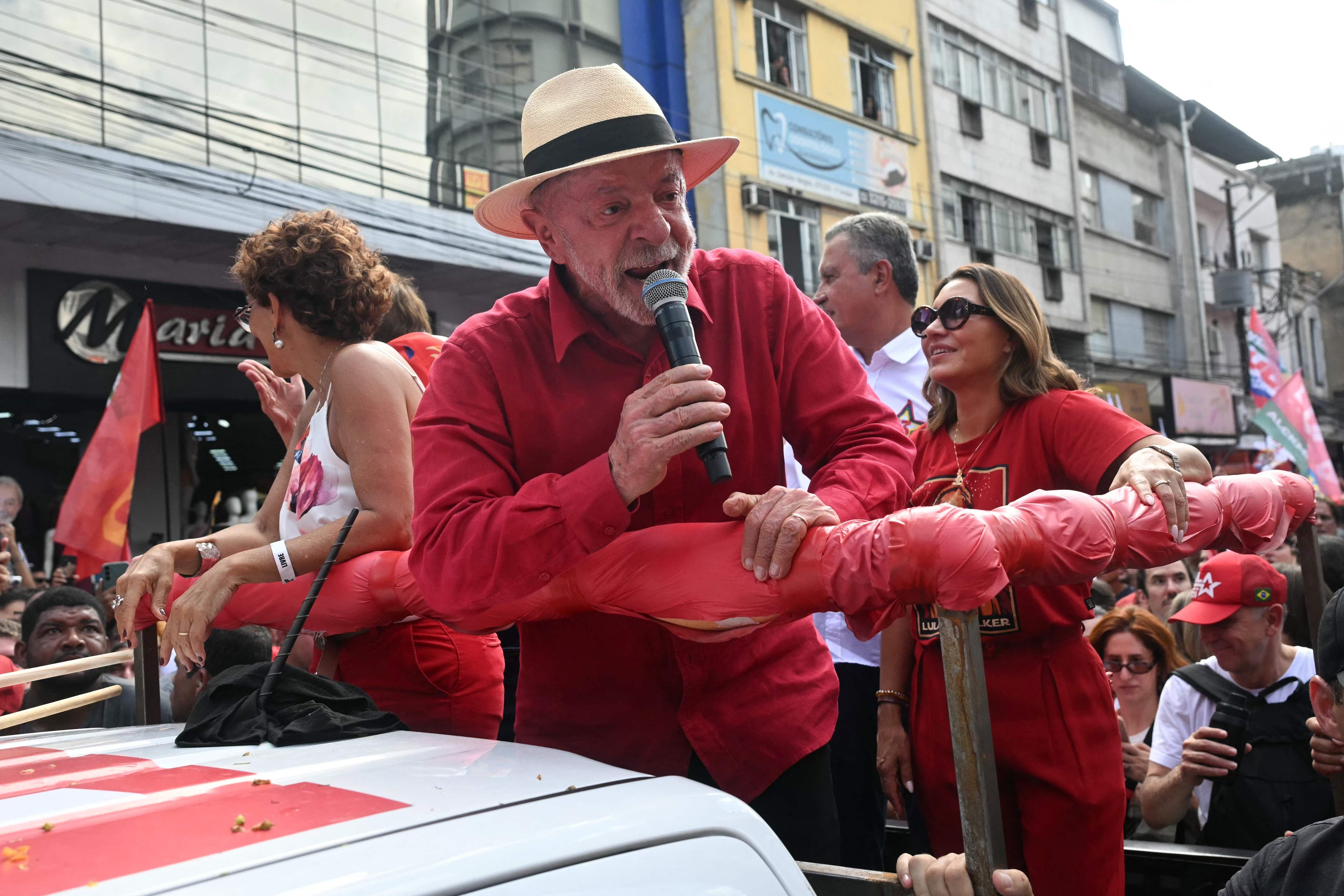 Ein Mann in rotem Hemd spricht bei einer Wahlkampfveranstaltung in einer Menschenmenge ins Mikrofon.