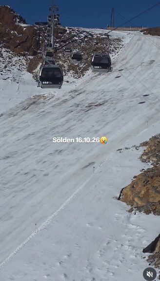 Seilbahn fährt über eine schneebedeckte, teilweise kahle Skipiste in Sölden.
