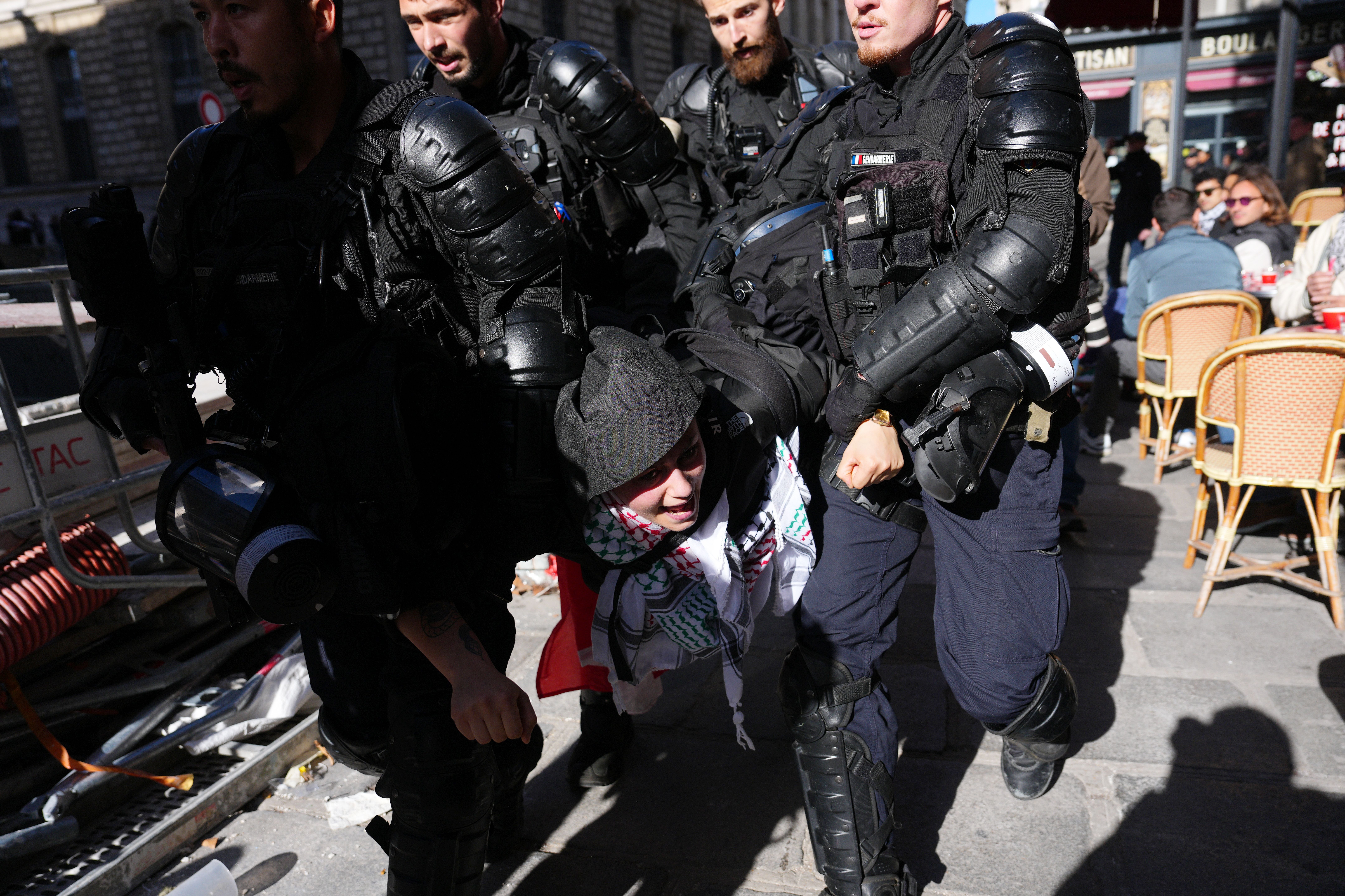 Polizisten in Schutzkleidung halten einen Demonstranten während eines Protests in Paris fest.