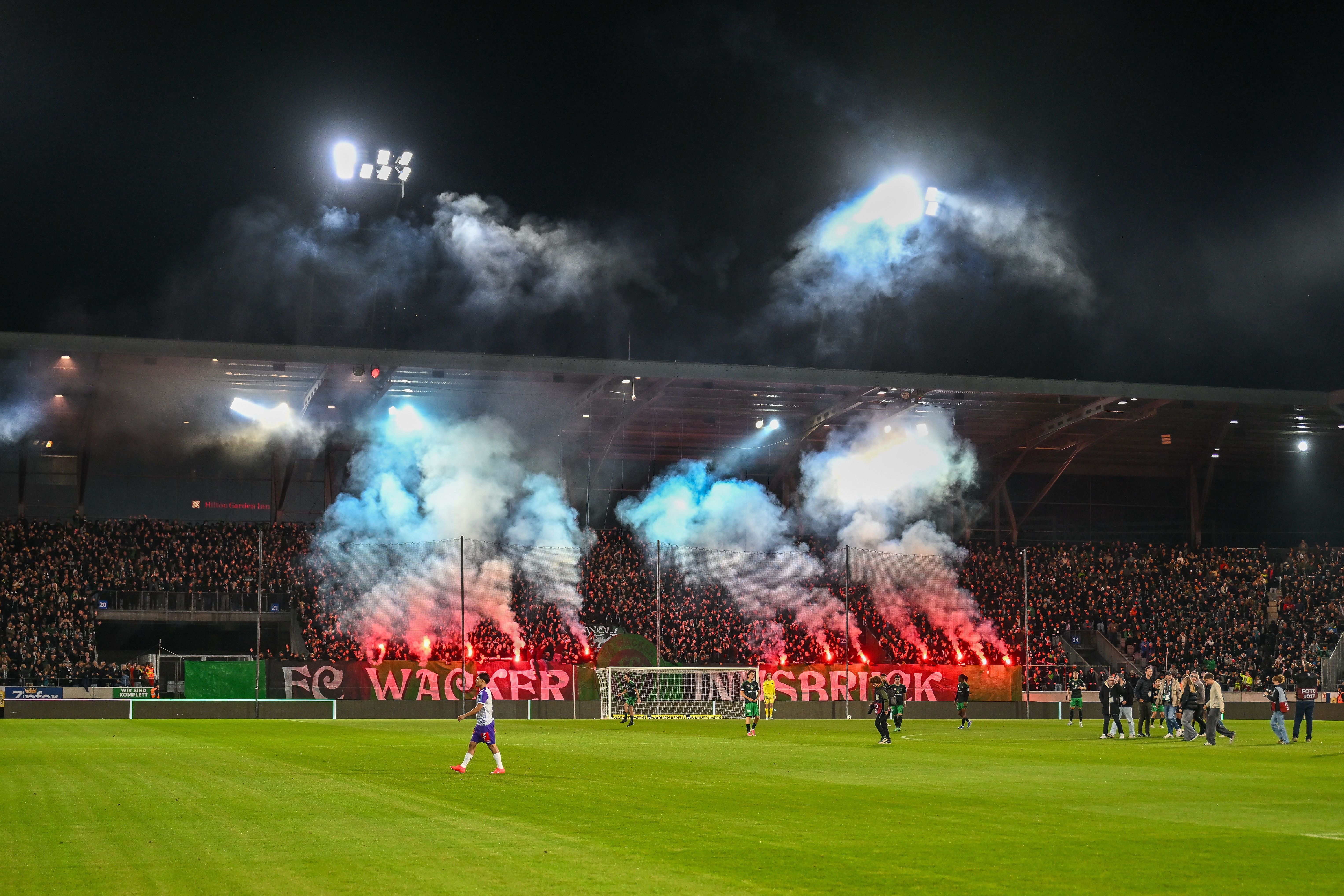 Fans von Wacker Innsbruck zünden Pyrotechnik im Stadion bei einem Fußballspiel am Abend.