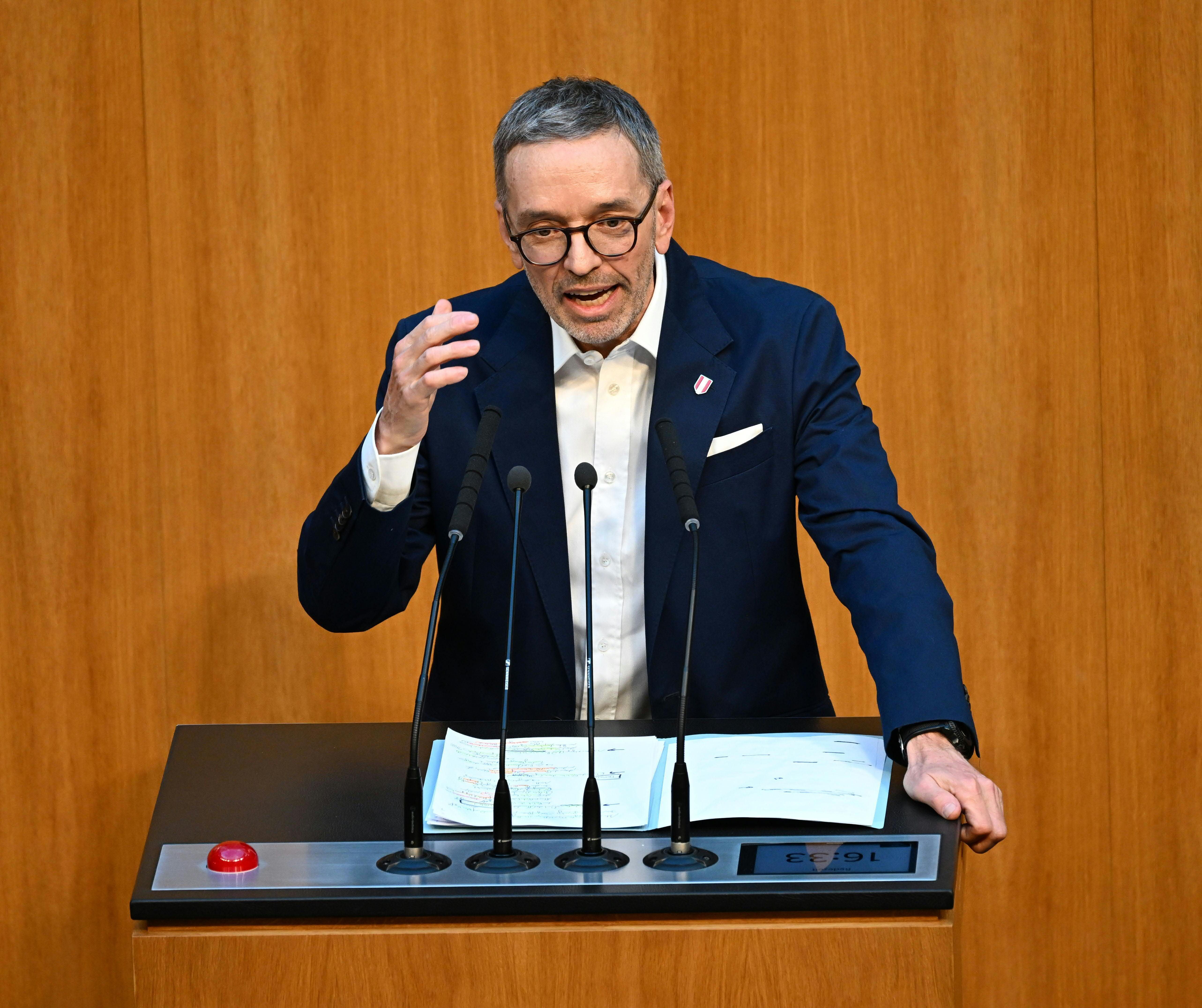 Ein Mann spricht gestikulierend an einem Rednerpult im Parlamentssaal.
