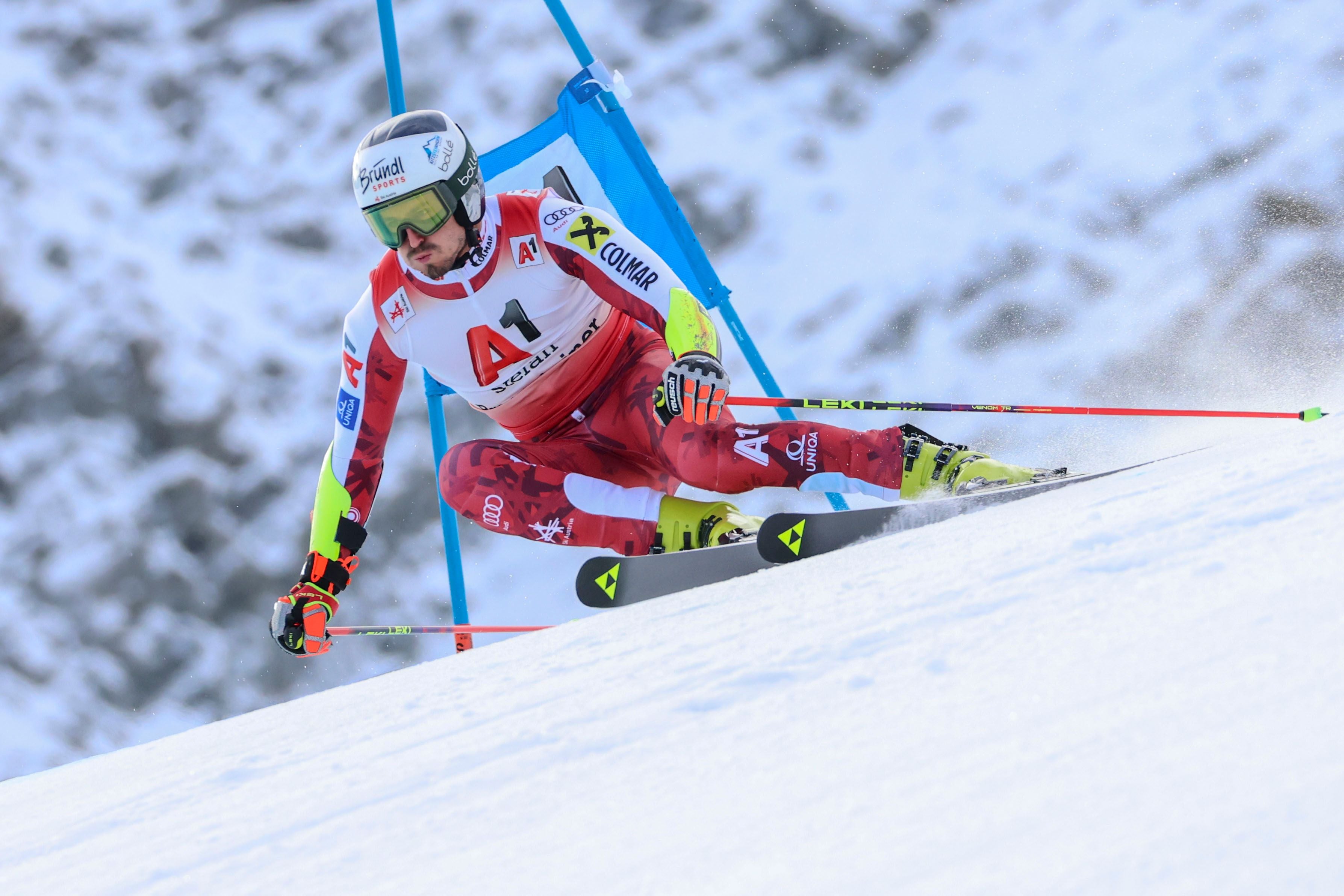 Ein Skirennläufer fährt im Riesenslalom auf einer schneebedeckten Piste mit schneller Kurve.