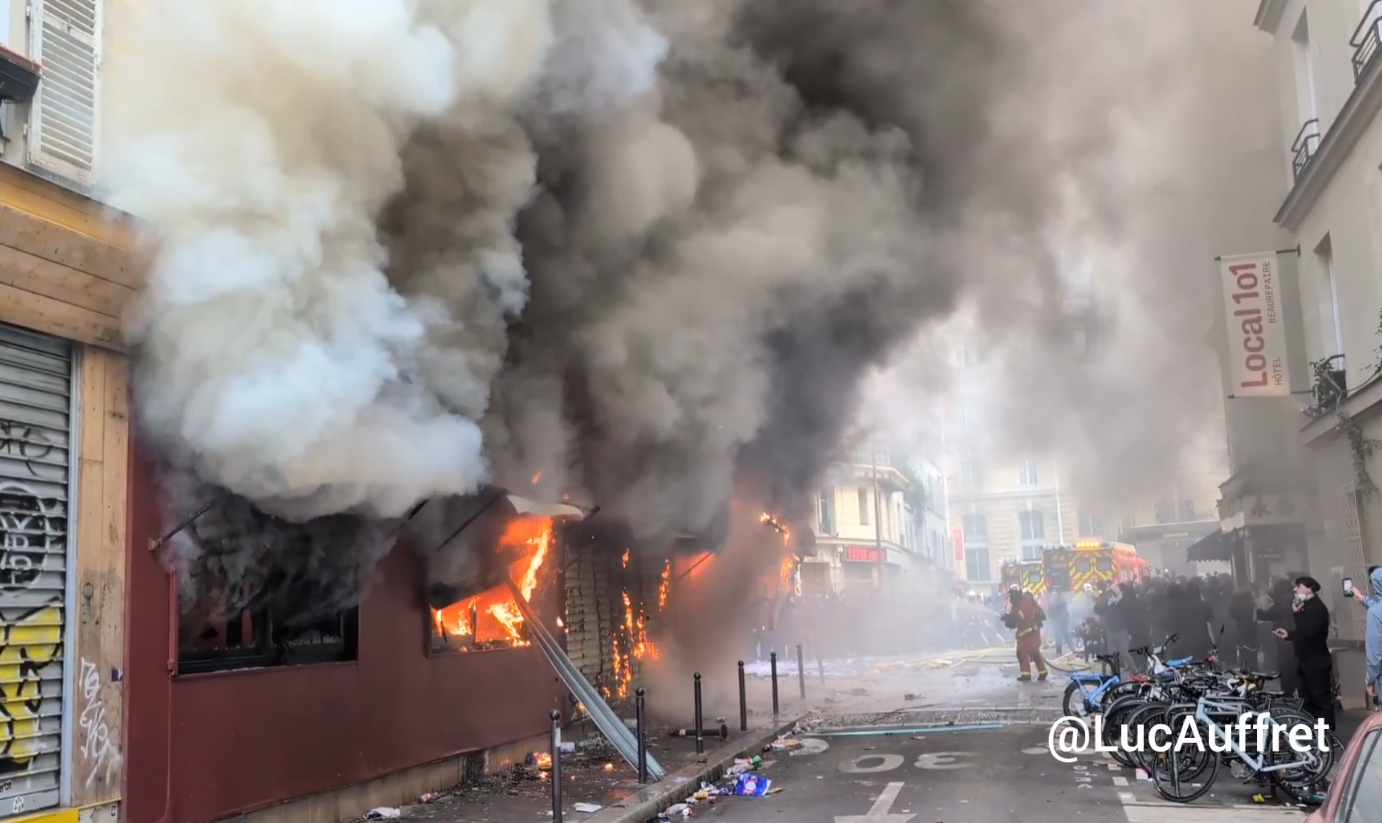 Dichter schwarzer Rauch und Flammen dringen aus einem brennenden Gebäude in einer Pariser Straße.