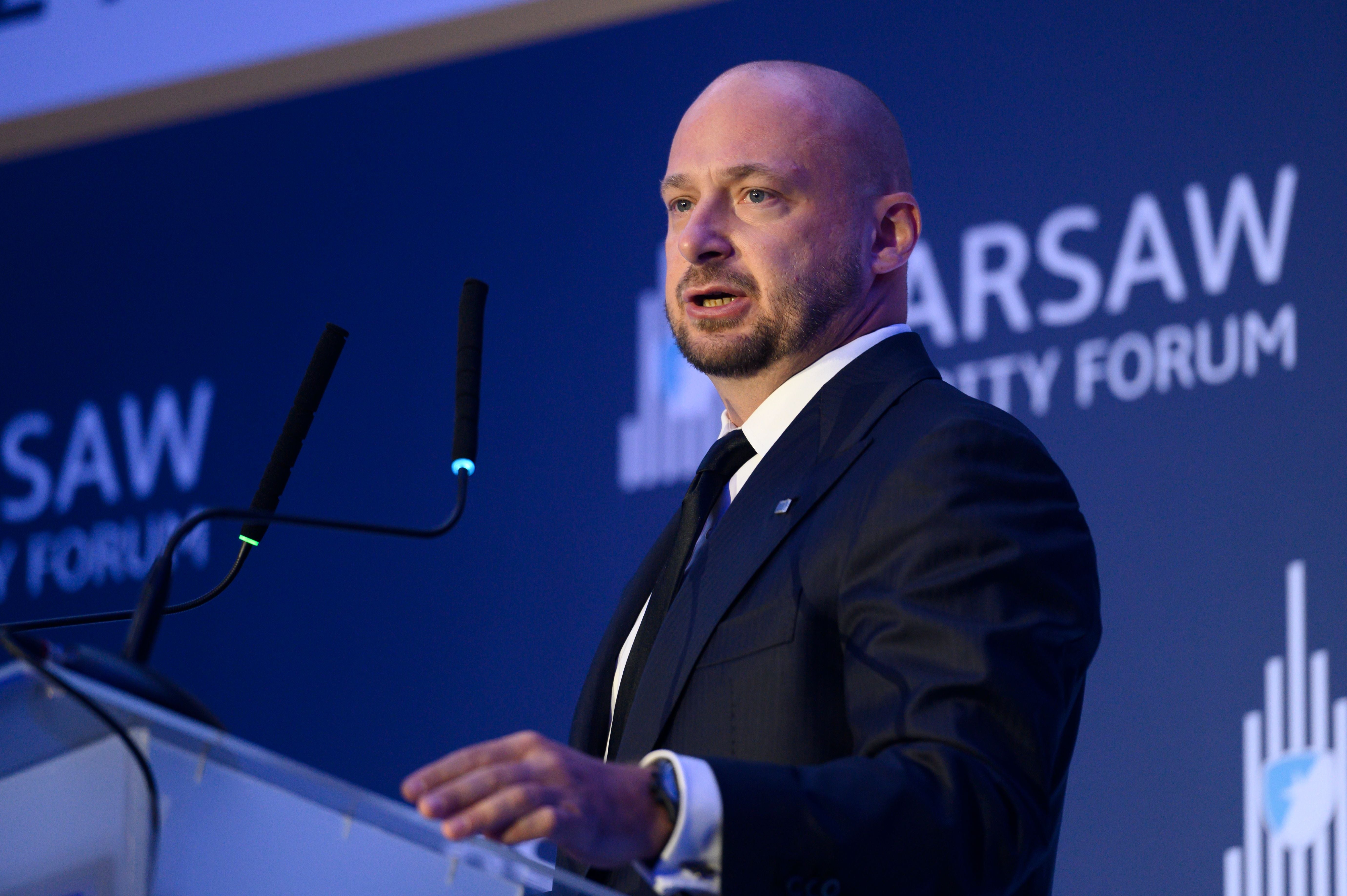 Mann im Anzug spricht auf dem Warsaw Security Forum 2024 am Rednerpult mit Mikrofonen.