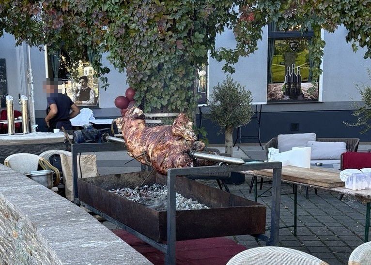 Ein ganzes Schwein wird draußen am Spieß über Holzkohle gegrillt.