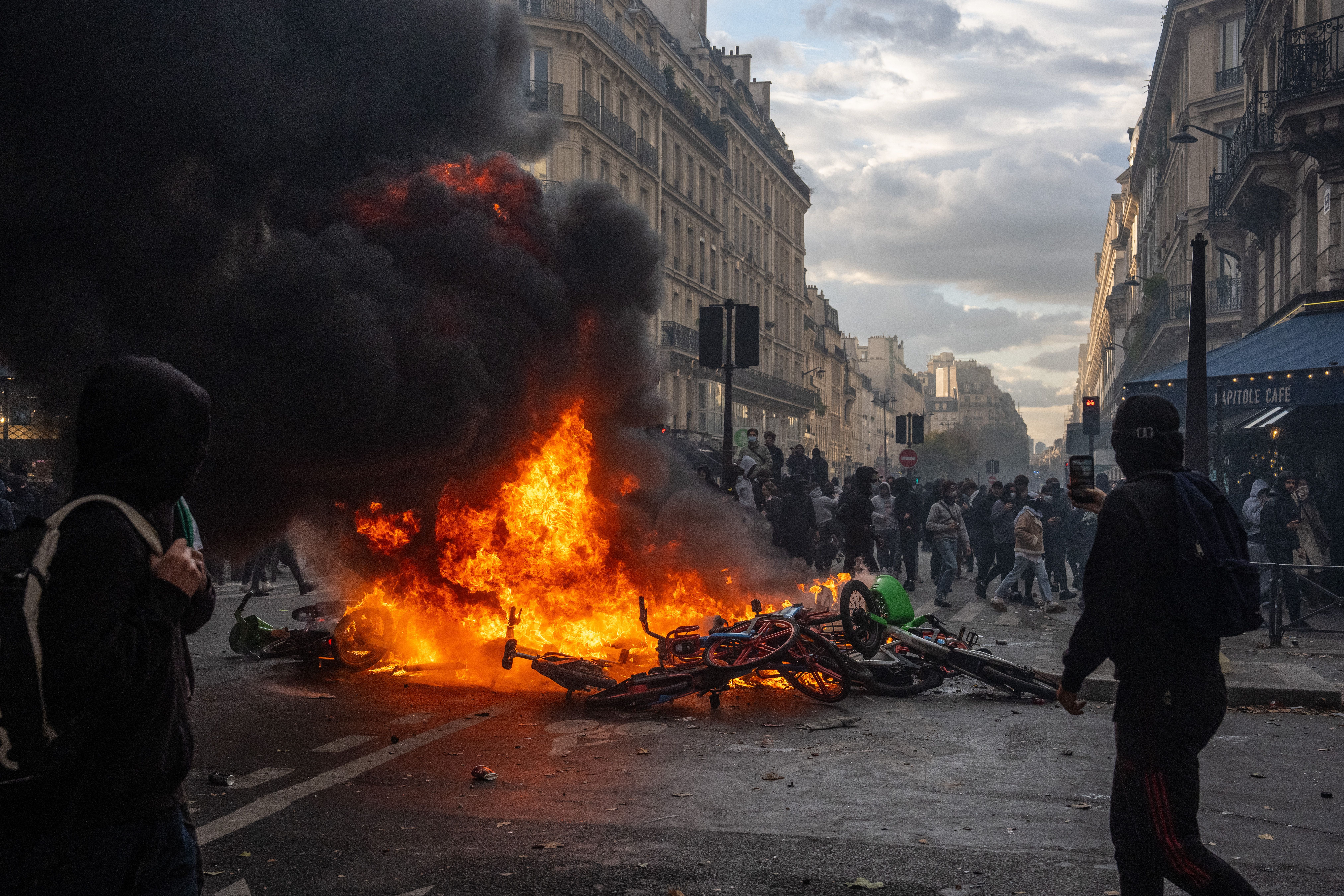 Ein großes Feuer mit dicker schwarzer Rauchwolke brennt auf einer Straße bei einer Demonstration in Paris.