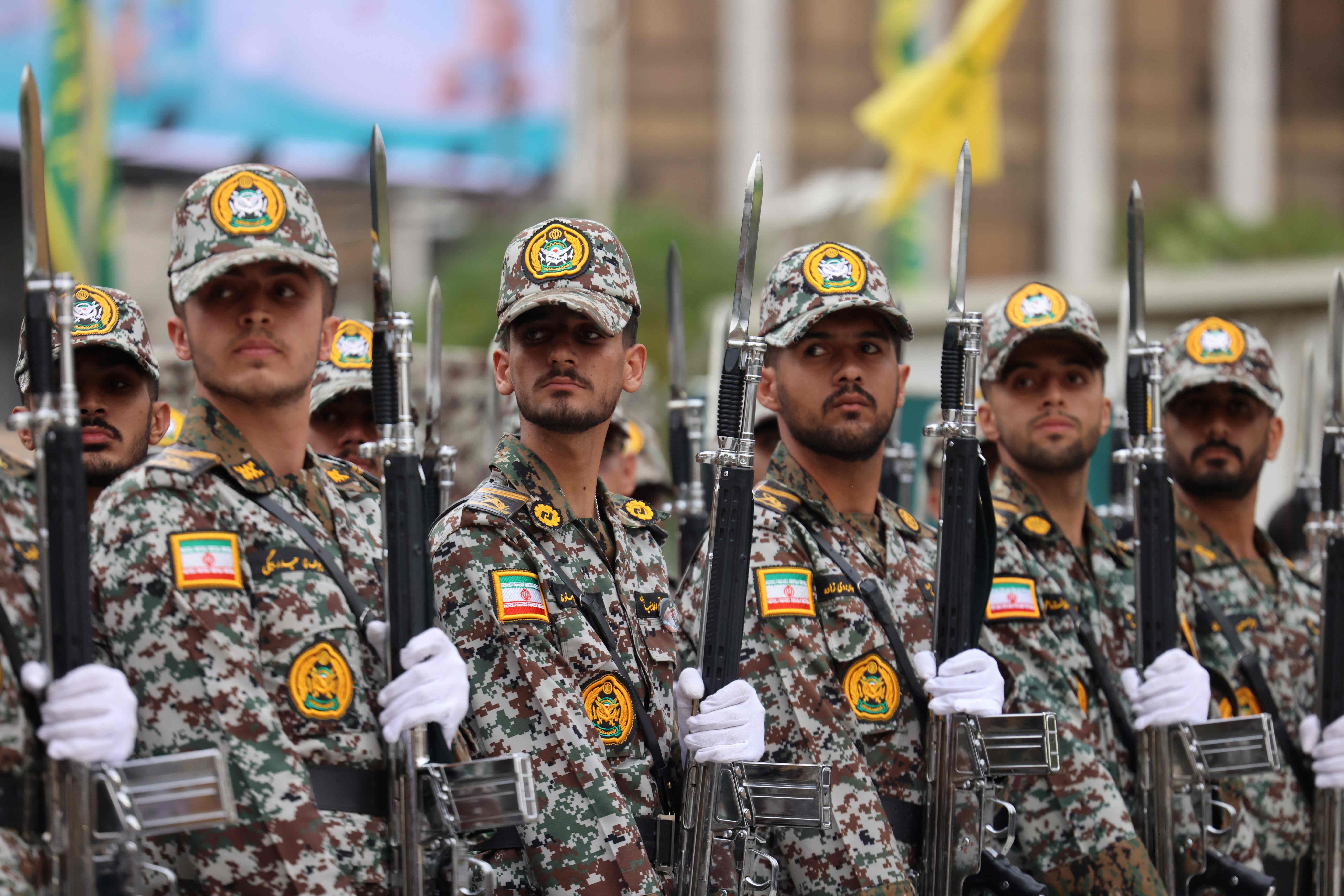 Iranische Soldaten in Tarnuniform mit Gewehren stehen bei einer Zeremonie in Reihe.