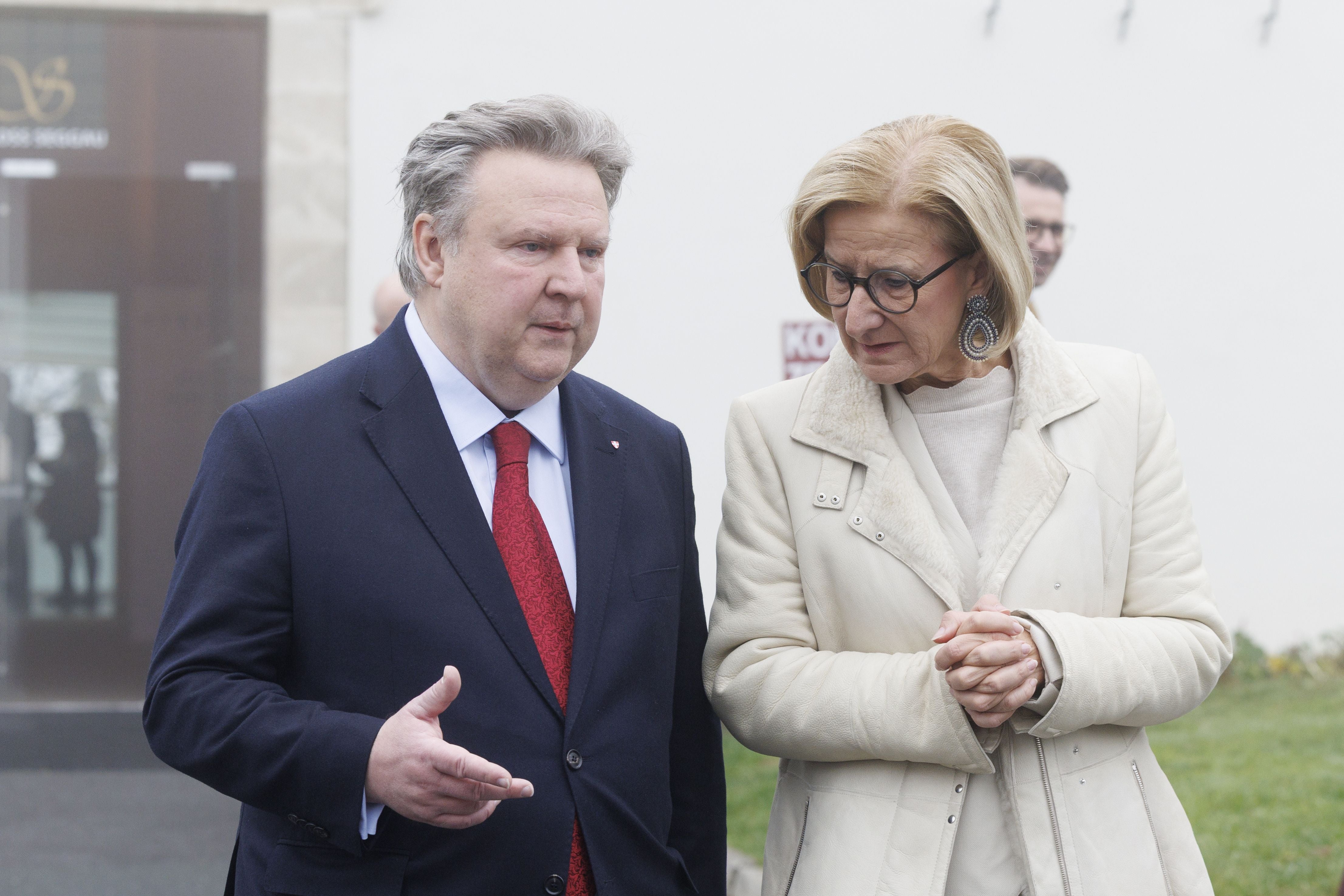 Zwei Personen sprechen im Freien bei einer Konferenz vor einem Gebäude.