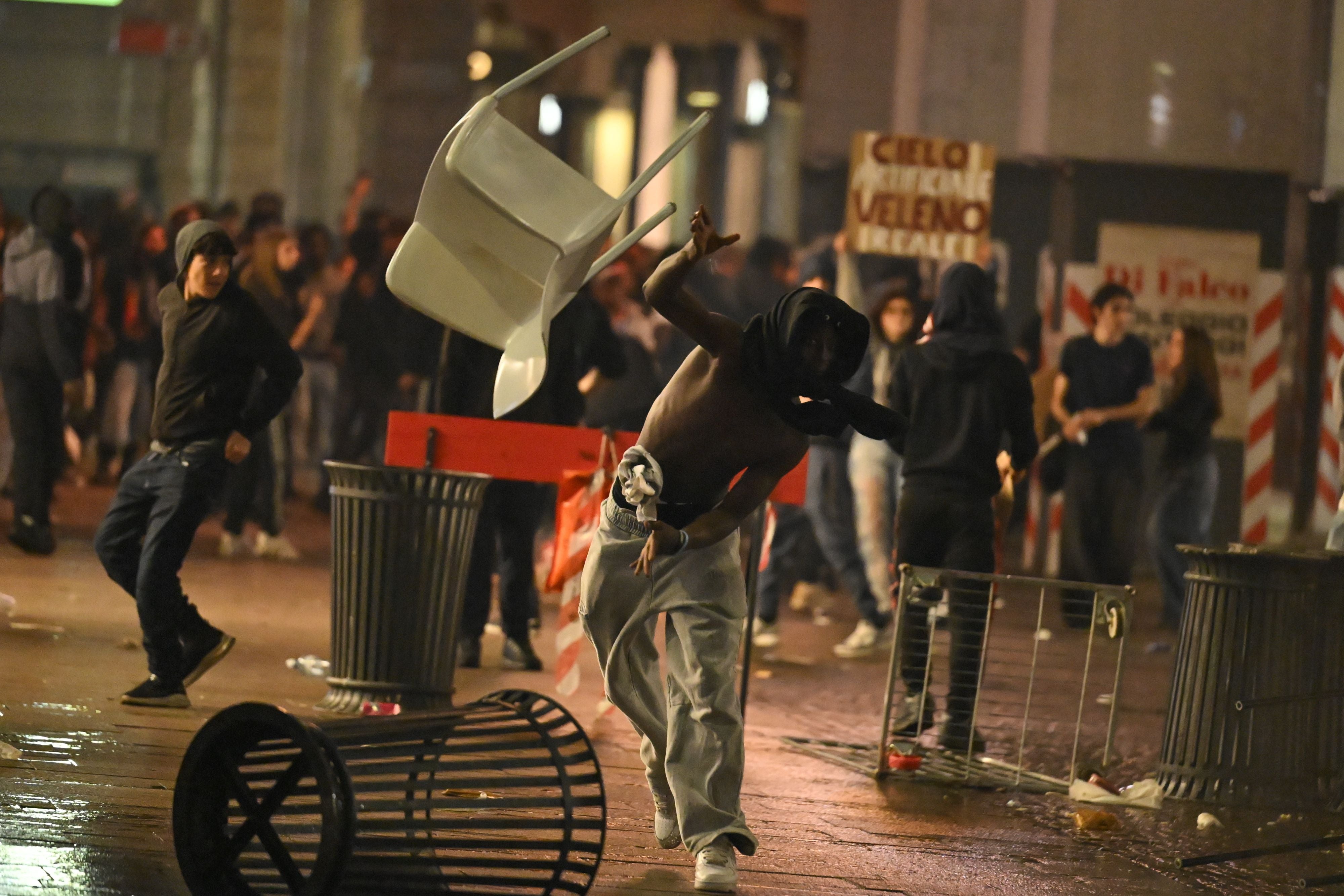 Demonstranten werfen Gegenstände bei einem Protest in Mailand; Unruhen auf der Straße.