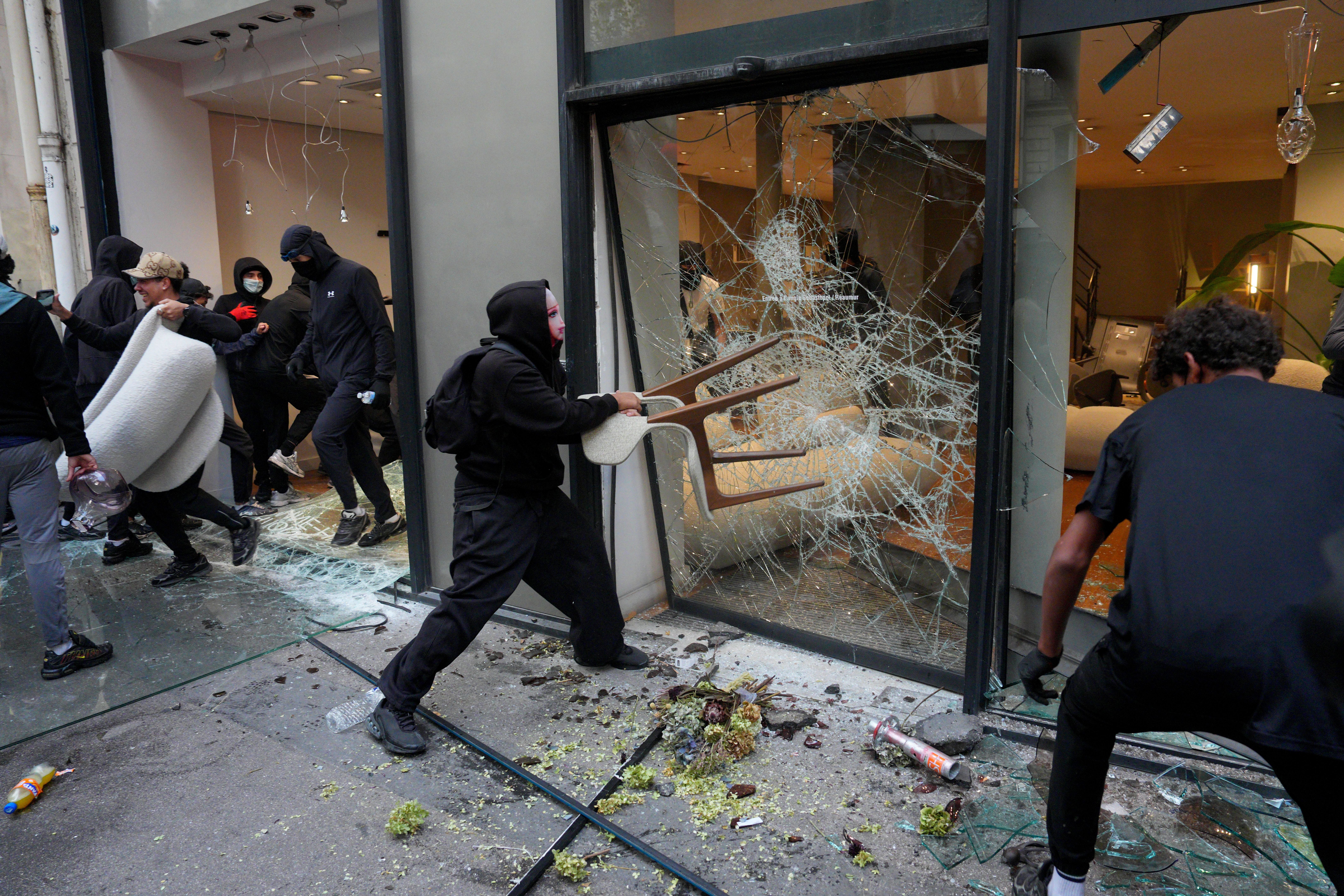 Vermummte Demonstranten zerstören Schaufenster und dringen in ein Geschäft in Paris ein.
