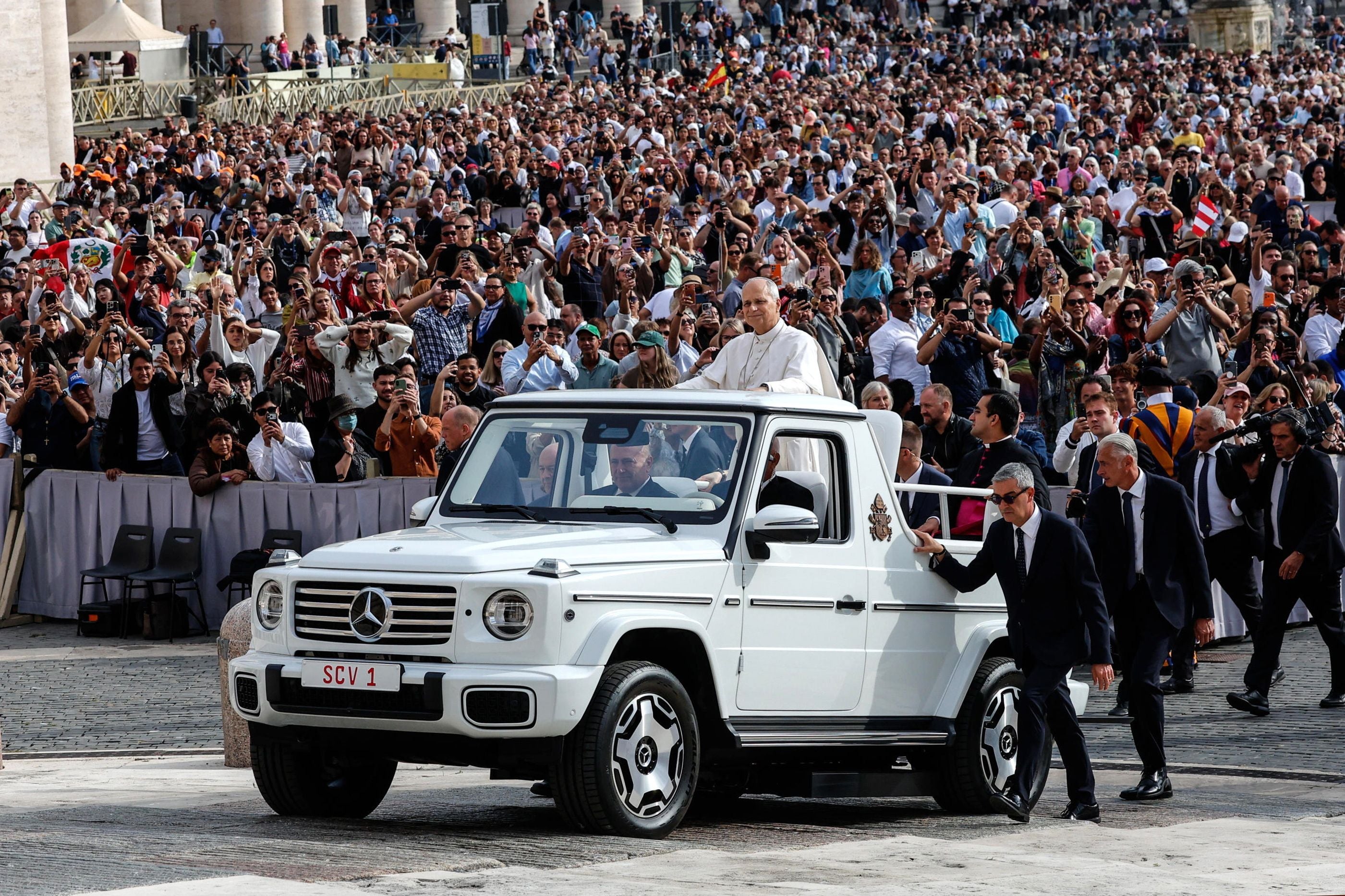 Der Papst fährt im weißen Papamobil an einer großen Menschenmenge am Petersplatz vorbei.