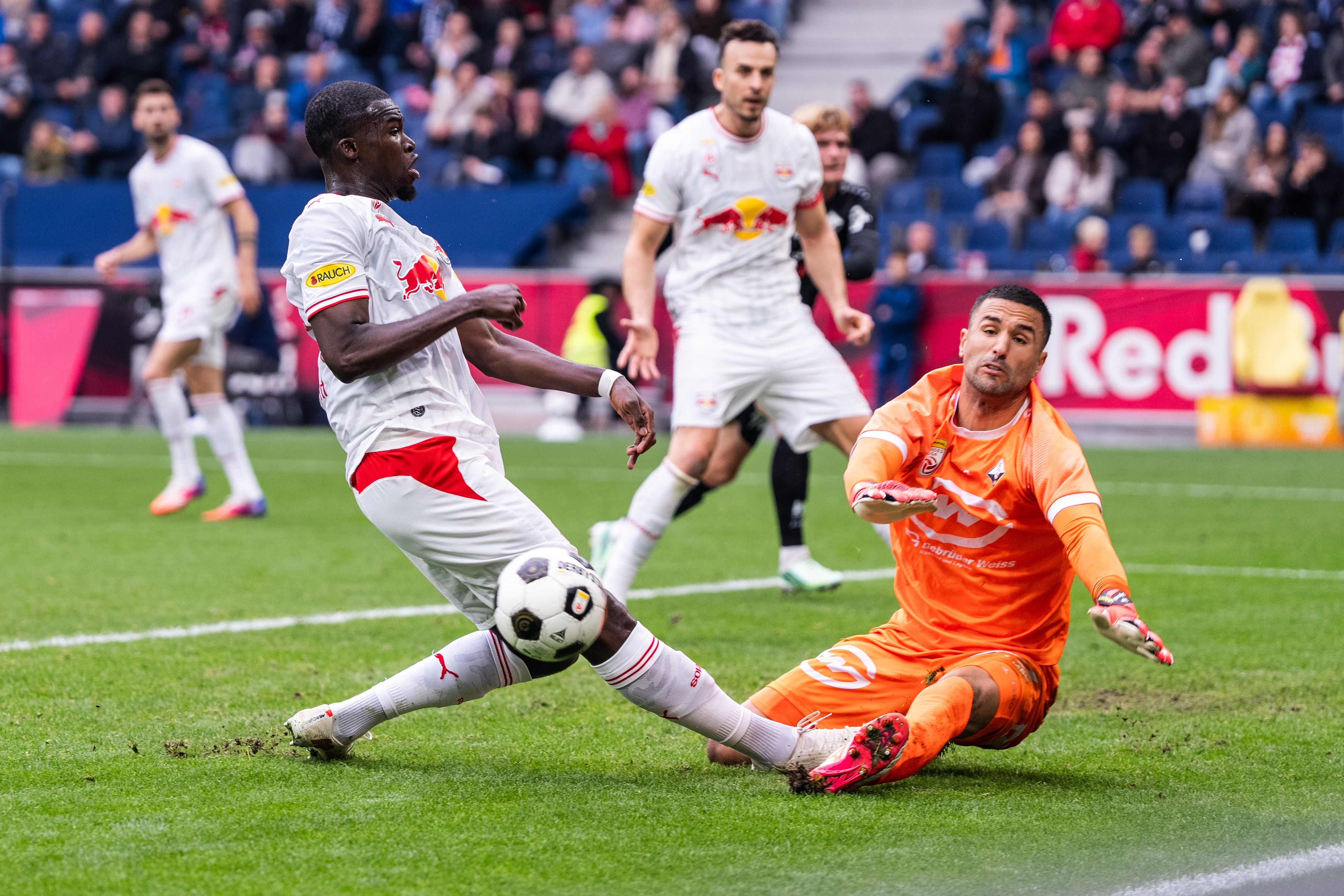 Ein Fußballspieler schießt am Torwart vorbei während eines Bundesliga-Spiels im Stadion.