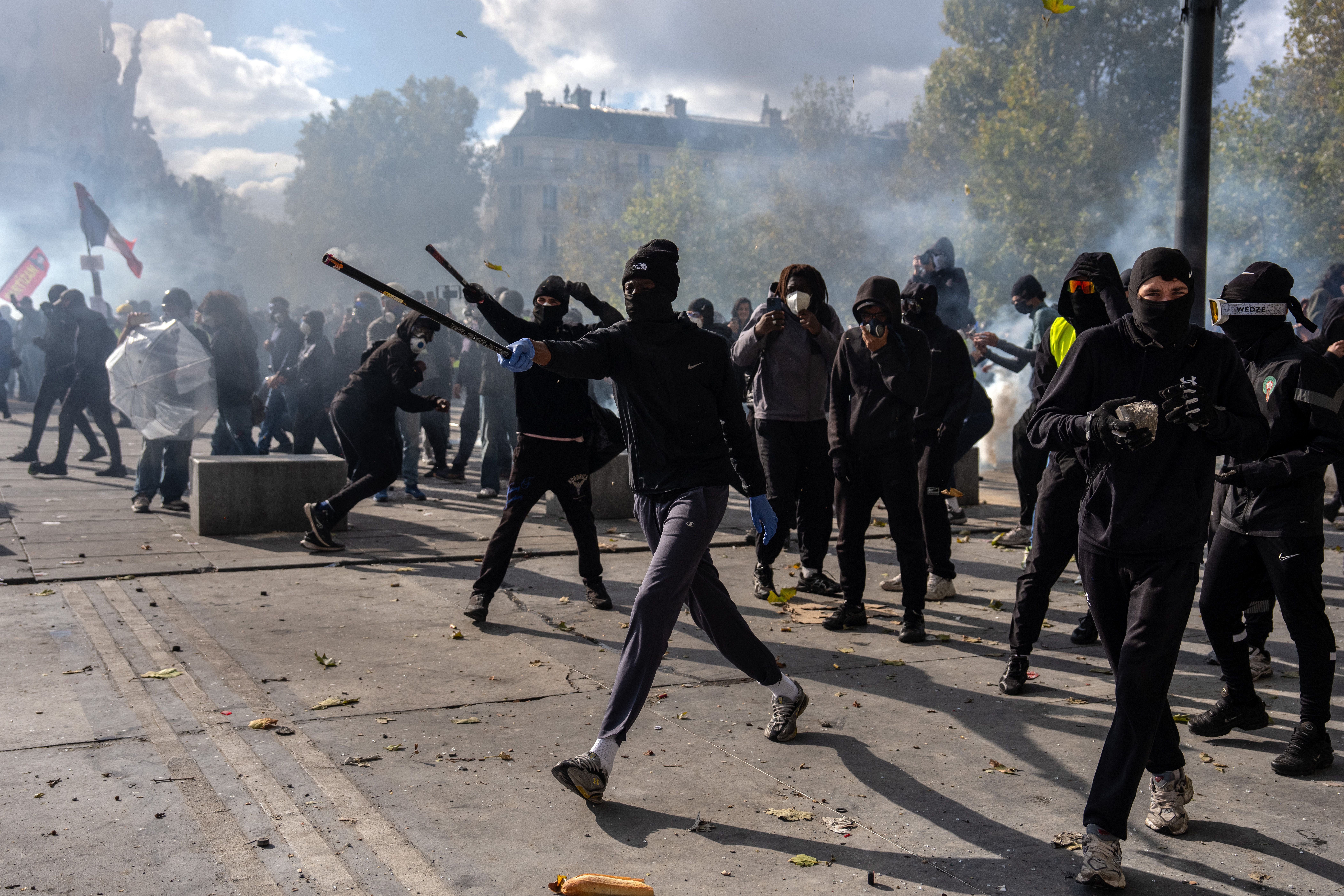 Maskierte Demonstranten werfen Gegenstände und schießen Feuerwerk während eines Protests in Paris.