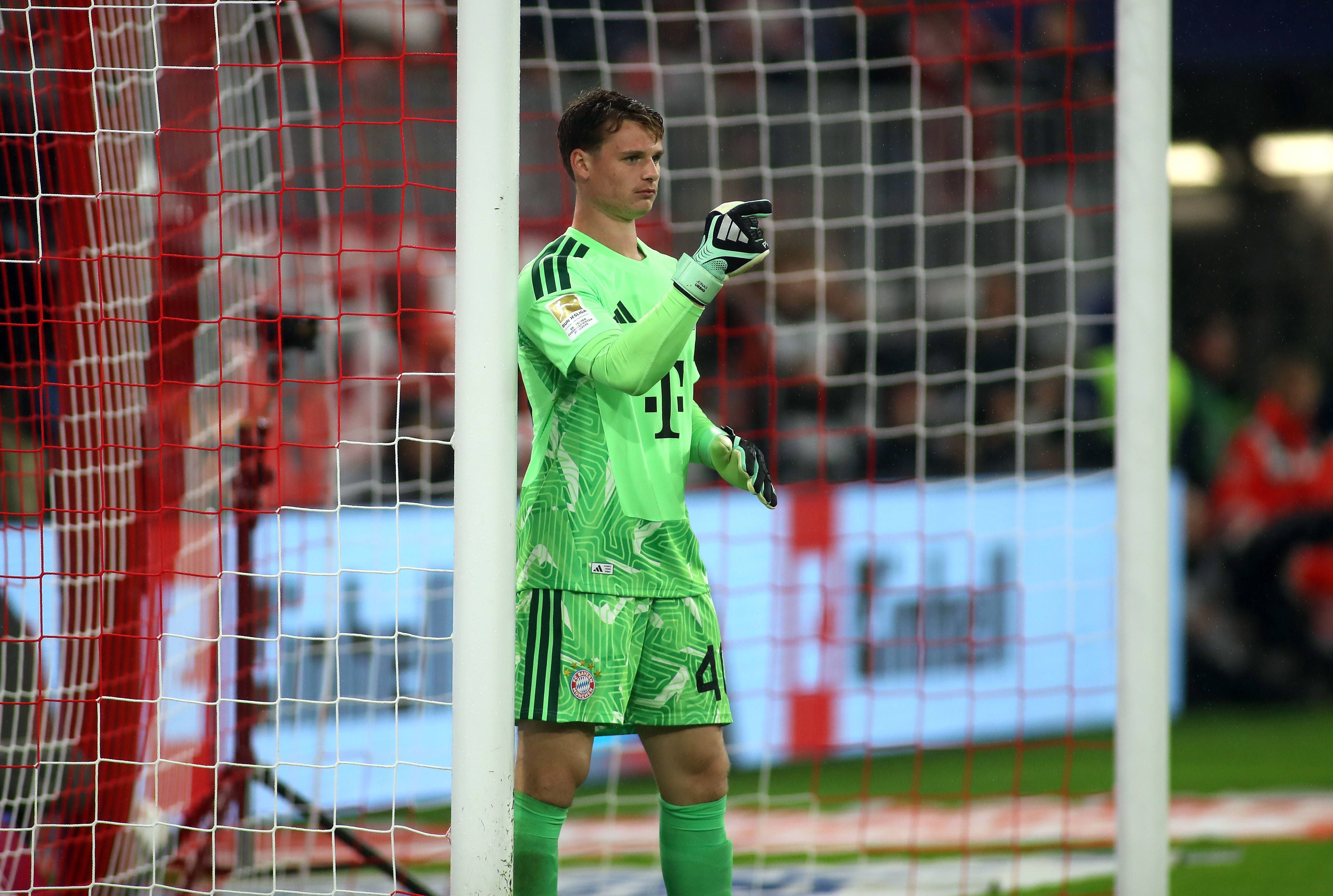 Torwart in grünem Trikot gibt laut gestikulierend Anweisungen vor dem Tor im Fußballstadion.